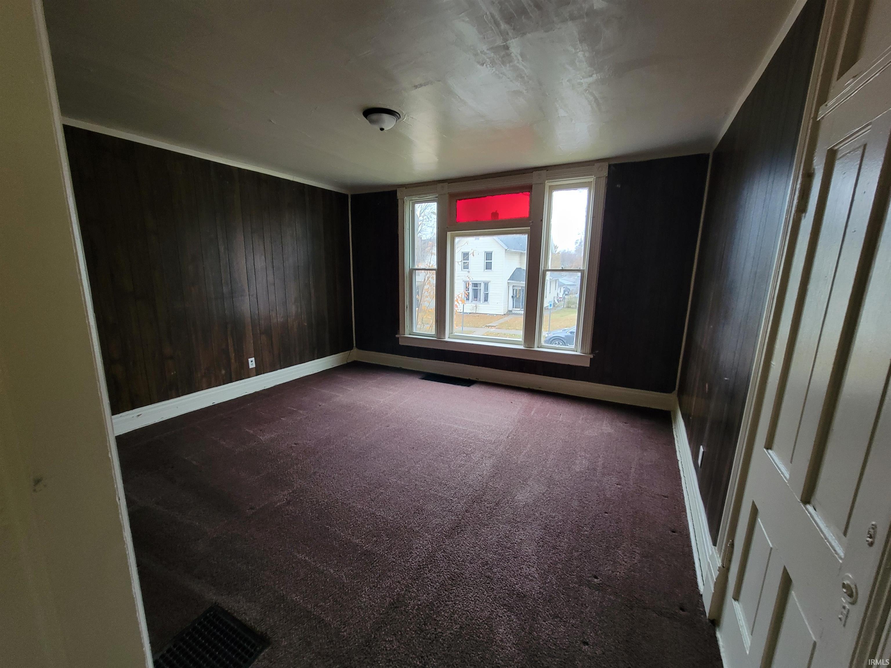 Empty room with dark colored carpet and wooden walls