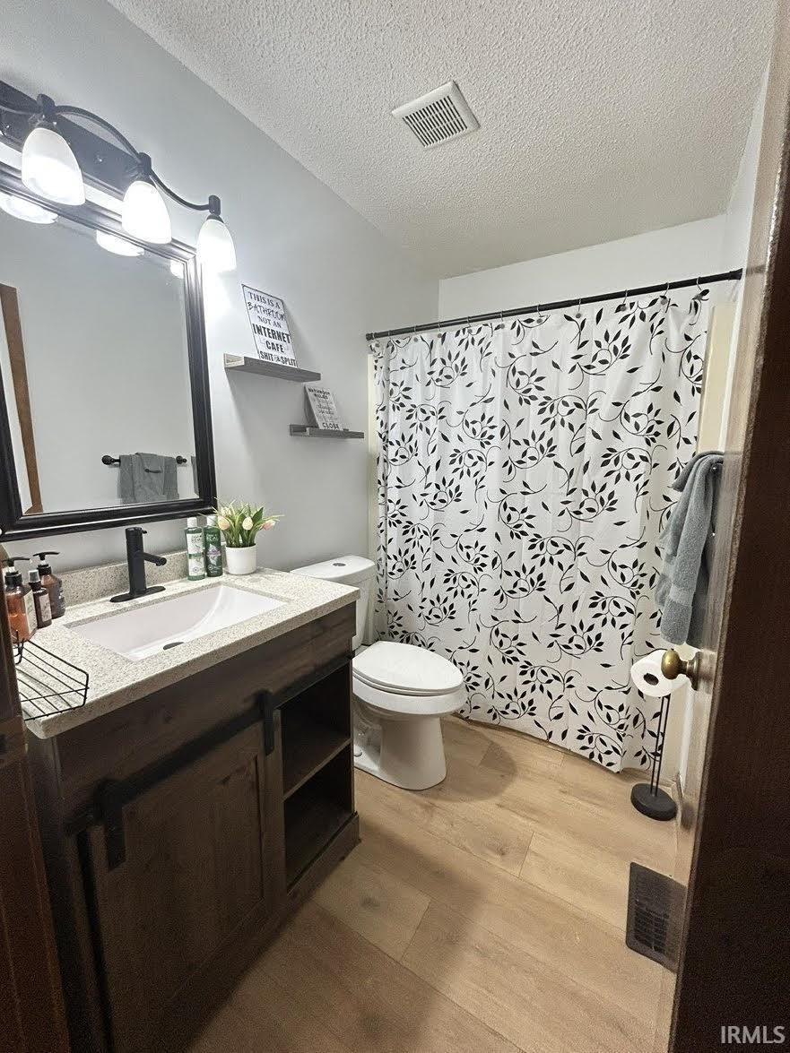Bathroom featuring vanity, light wood-style floors, curtained shower, and a textured ceiling