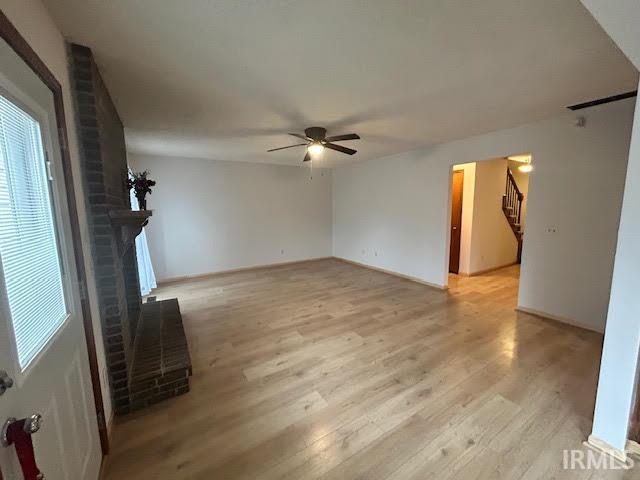 Unfurnished living room with light wood-style flooring, ceiling fan, and a fireplace