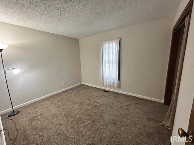 Unfurnished bedroom with dark colored carpet and a textured ceiling