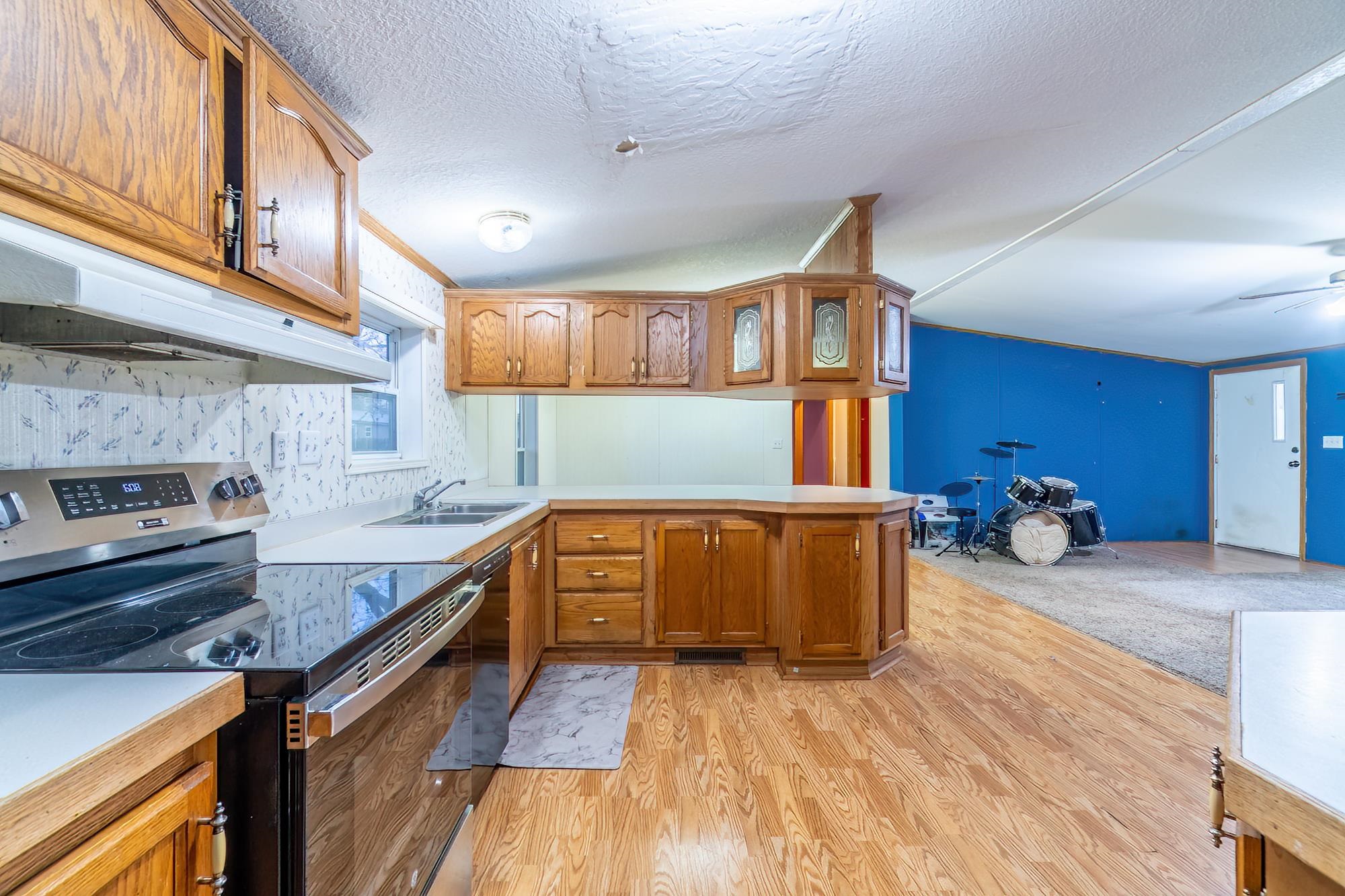 Kitchen with stainless steel range with electric cooktop, light countertops, brown cabinets, a peninsula, and a textured ceiling
