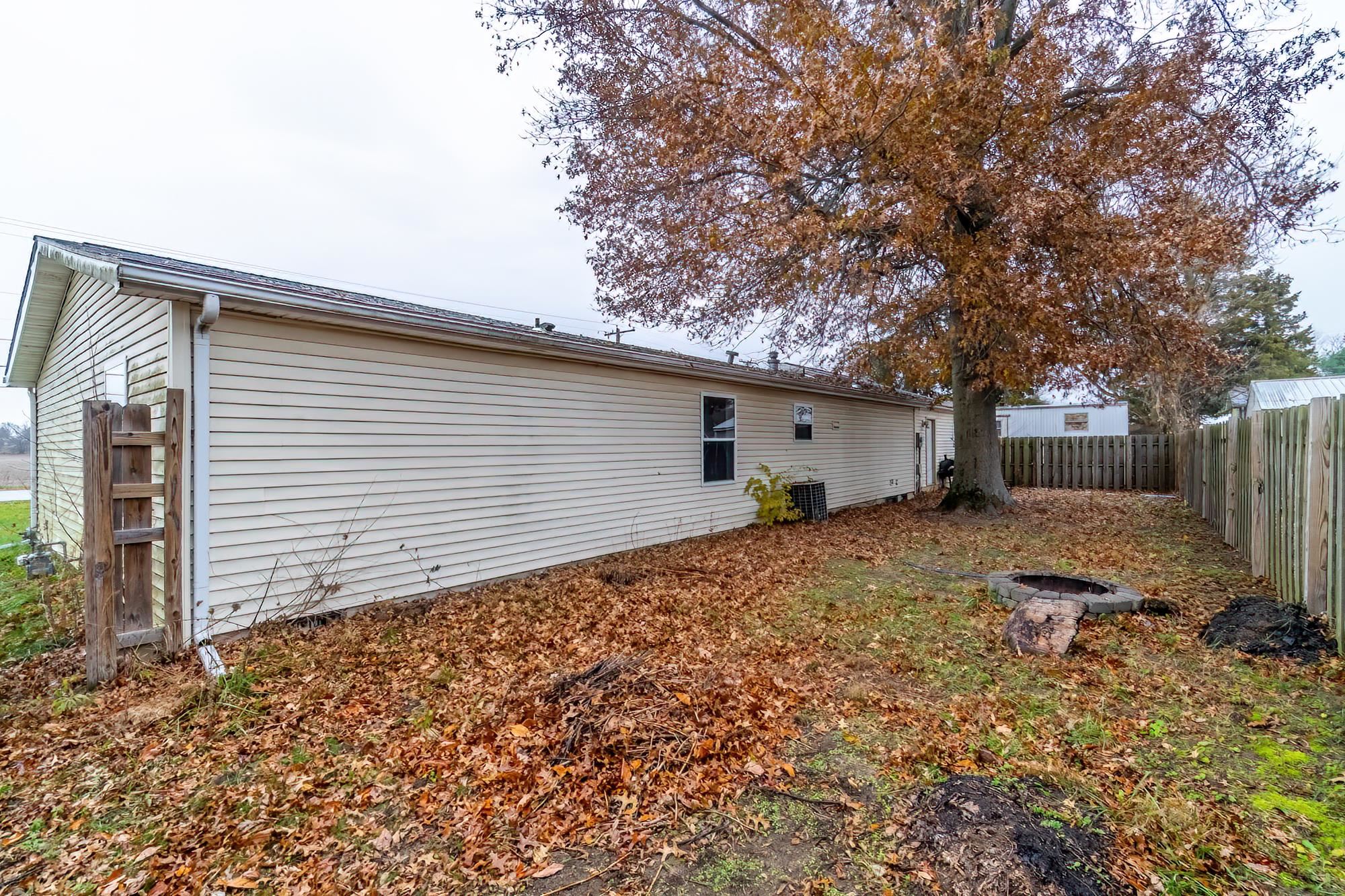 Back of house with a fenced backyard and an outdoor fire pit