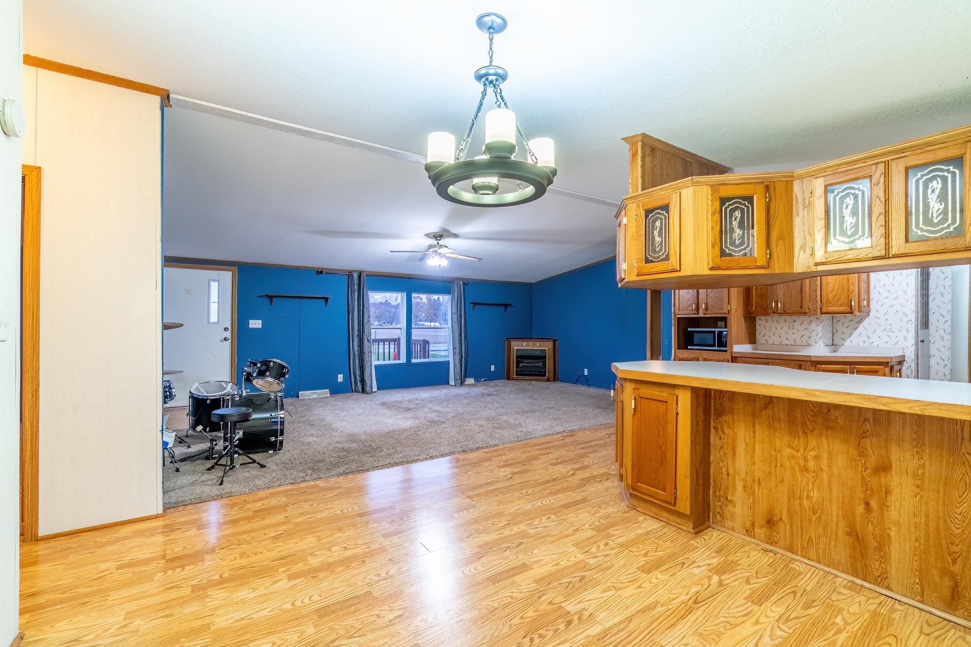 Kitchen with light countertops, brown cabinetry, light wood-type flooring, and hanging light fixtures