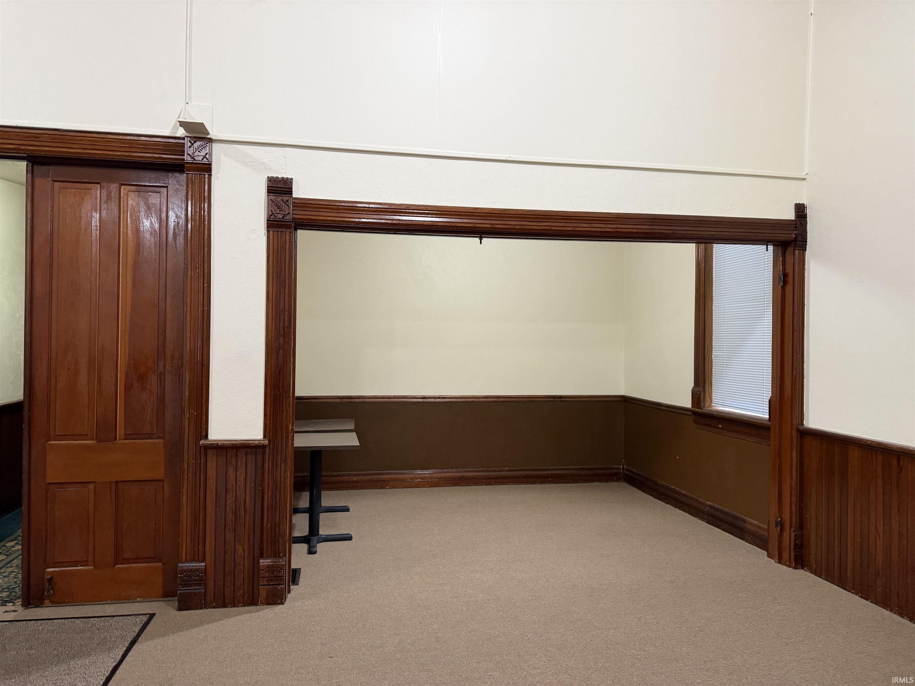 Unfurnished office featuring wainscoting, light carpet, and wood walls