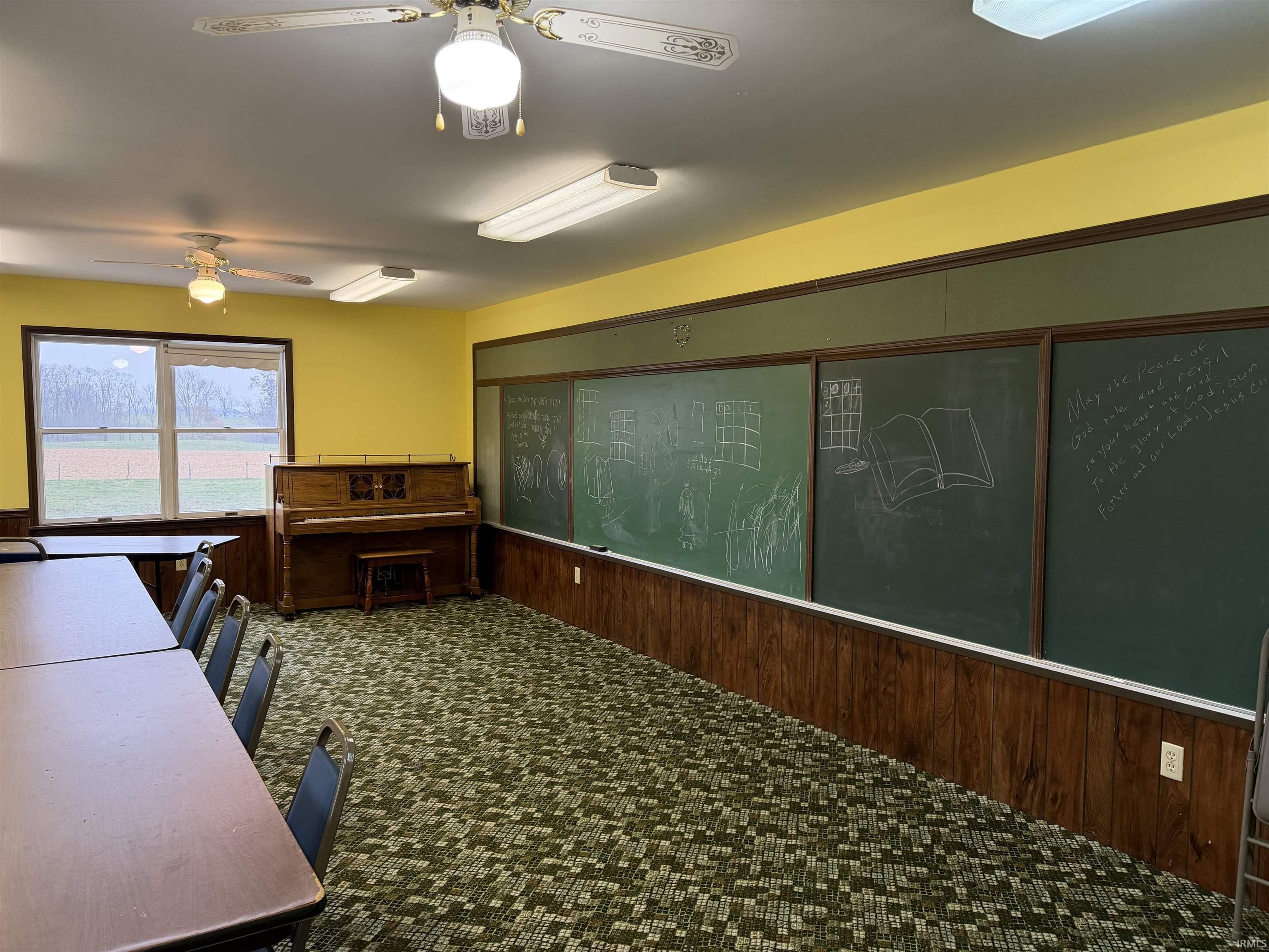 Classroom with wood walls, wainscoting, and a ceiling fan