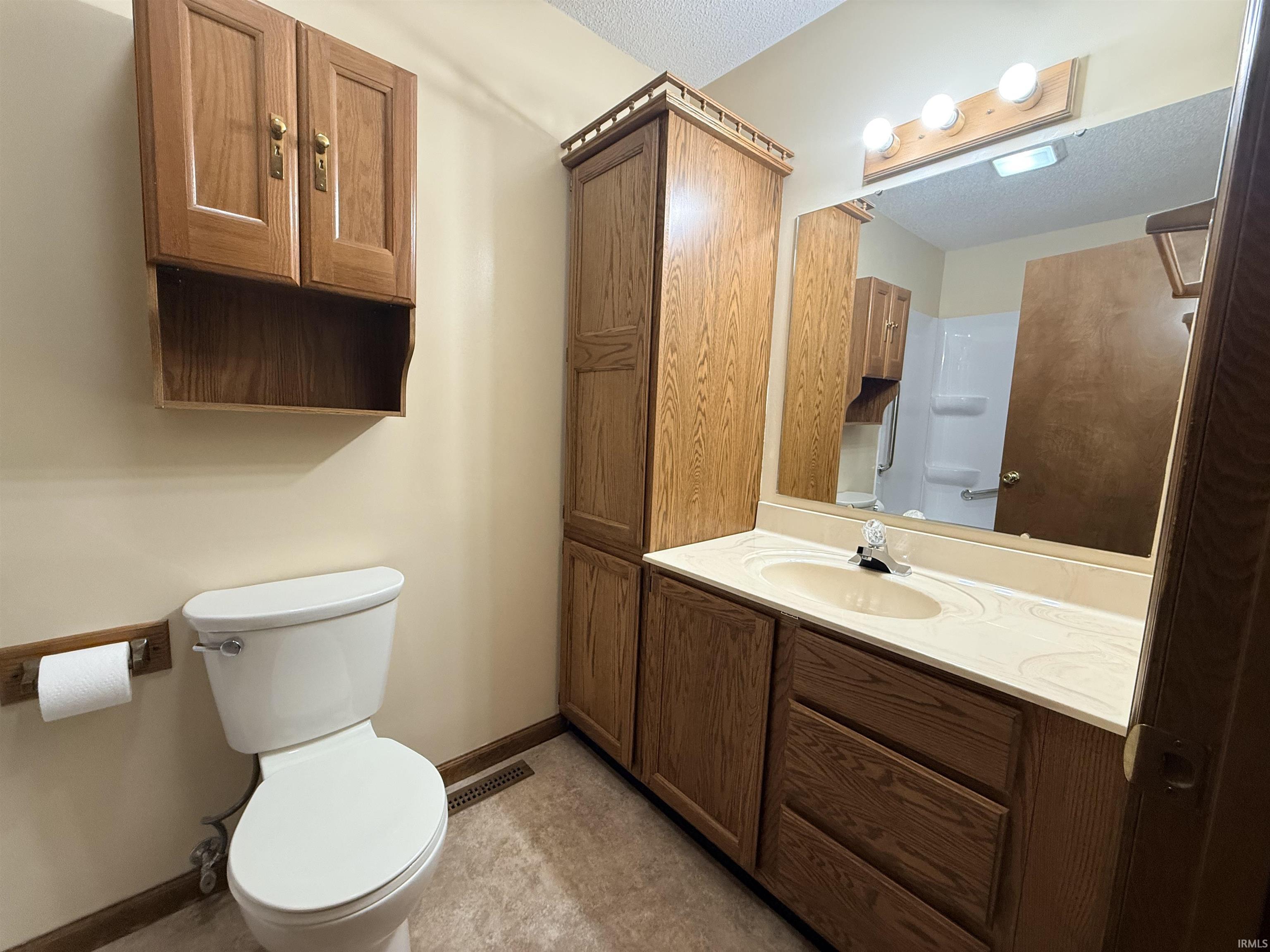Bathroom featuring vanity, a shower, and a textured ceiling