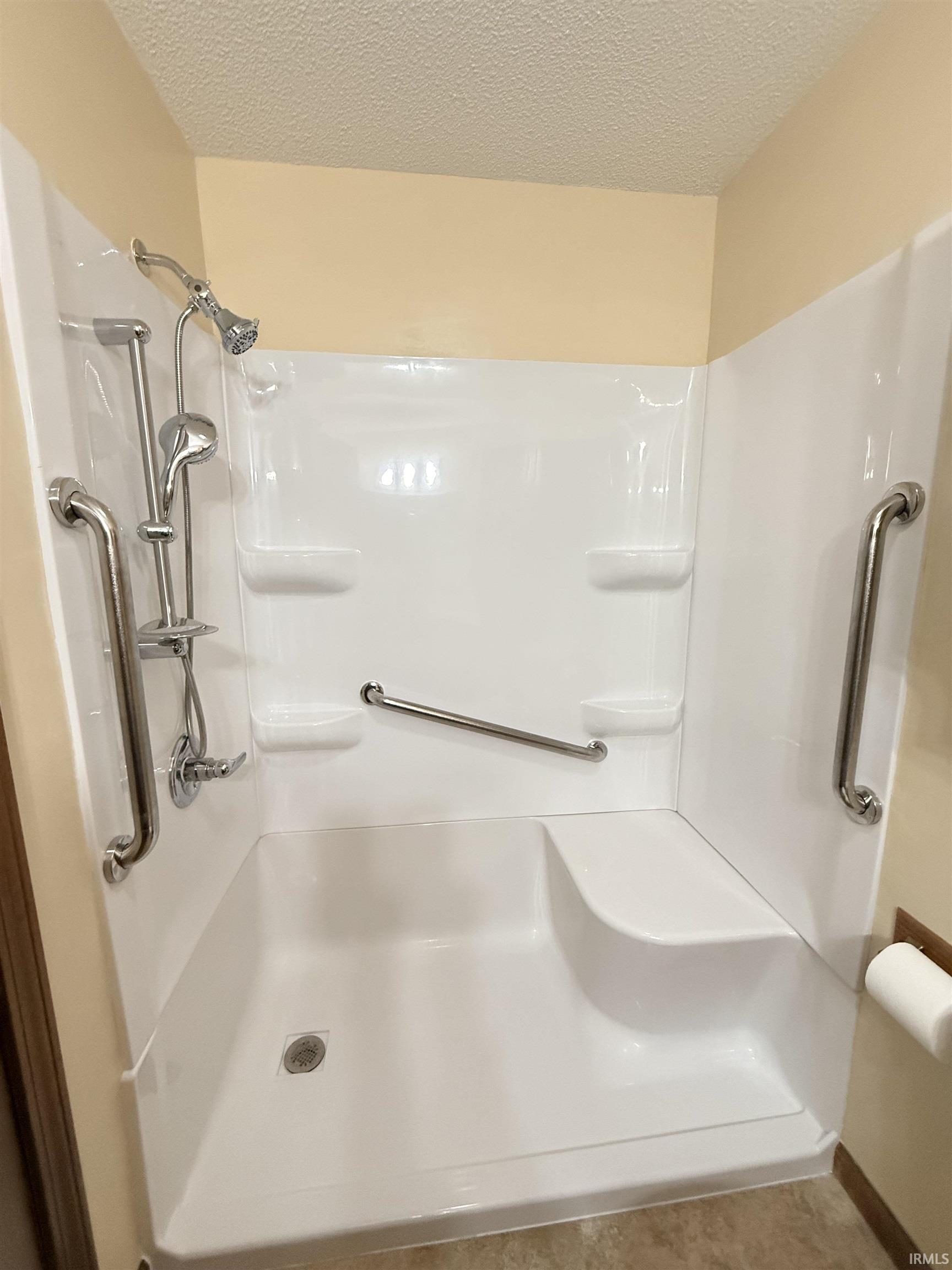 Bathroom featuring a textured ceiling, a shower, and tile patterned floors
