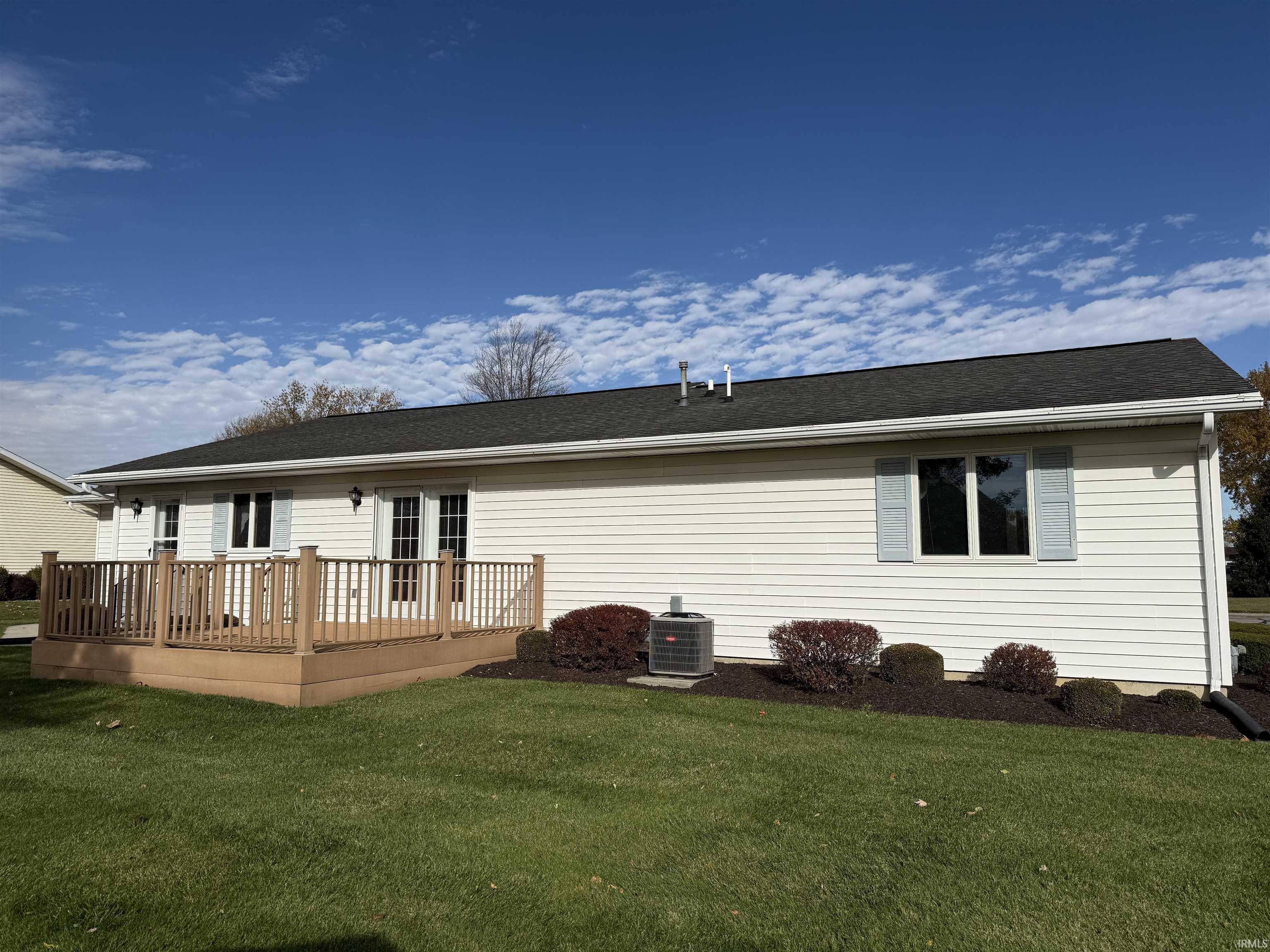 Back of house featuring a wooden deck, a yard, and a shingled roof