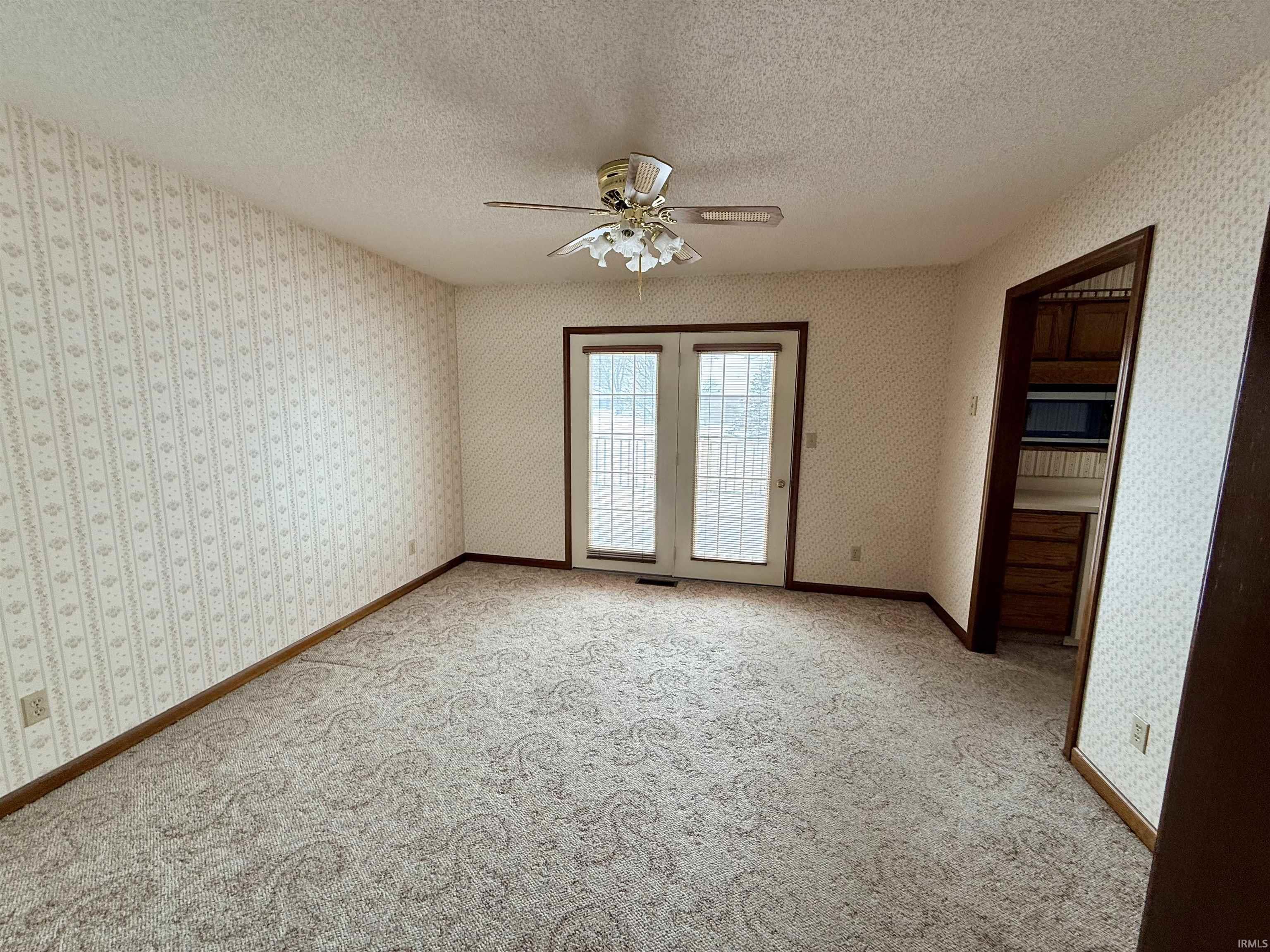 Unfurnished room with a ceiling fan, a textured ceiling, carpet flooring, and wallpapered walls