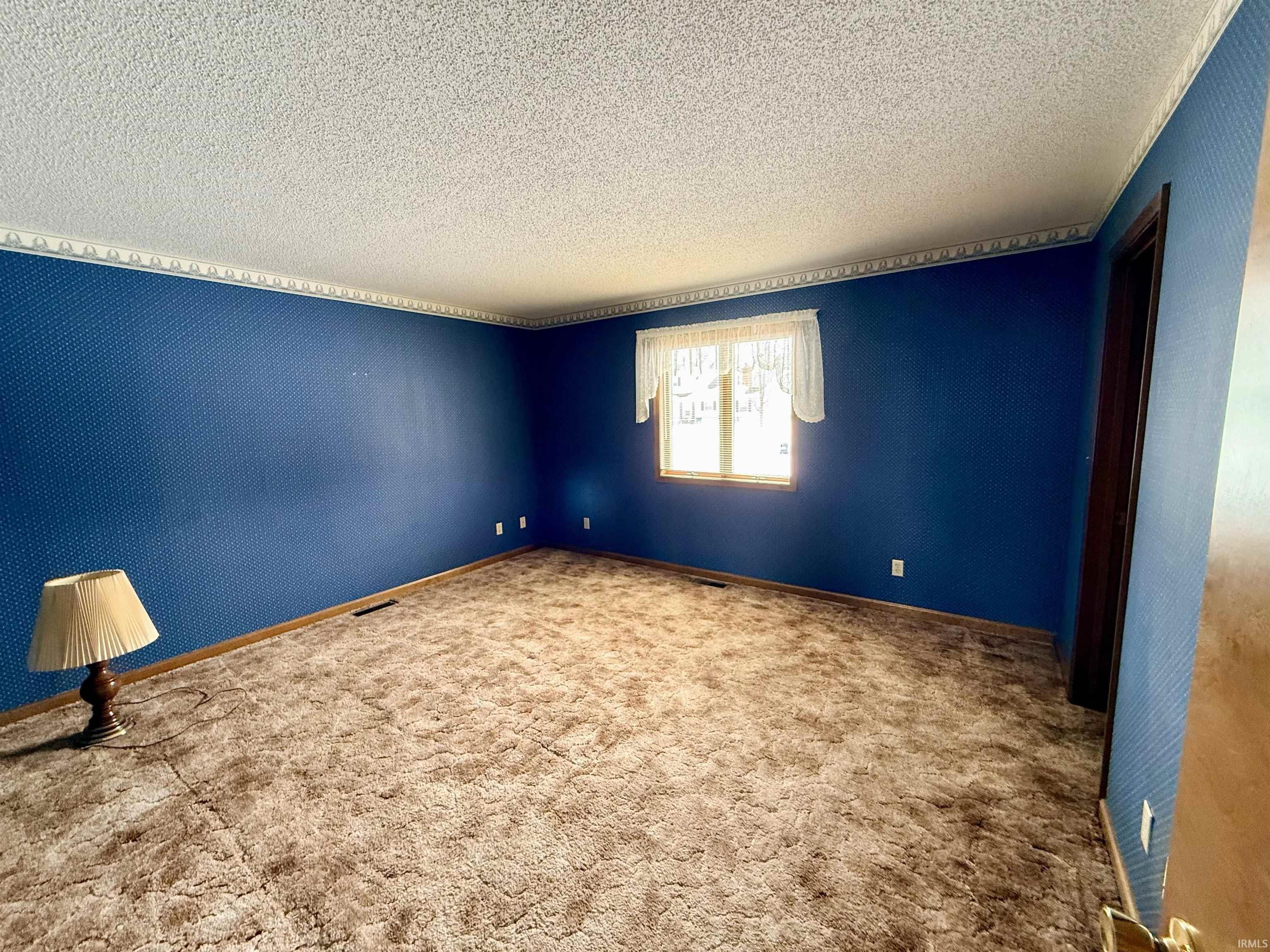 Carpeted empty room featuring a textured ceiling