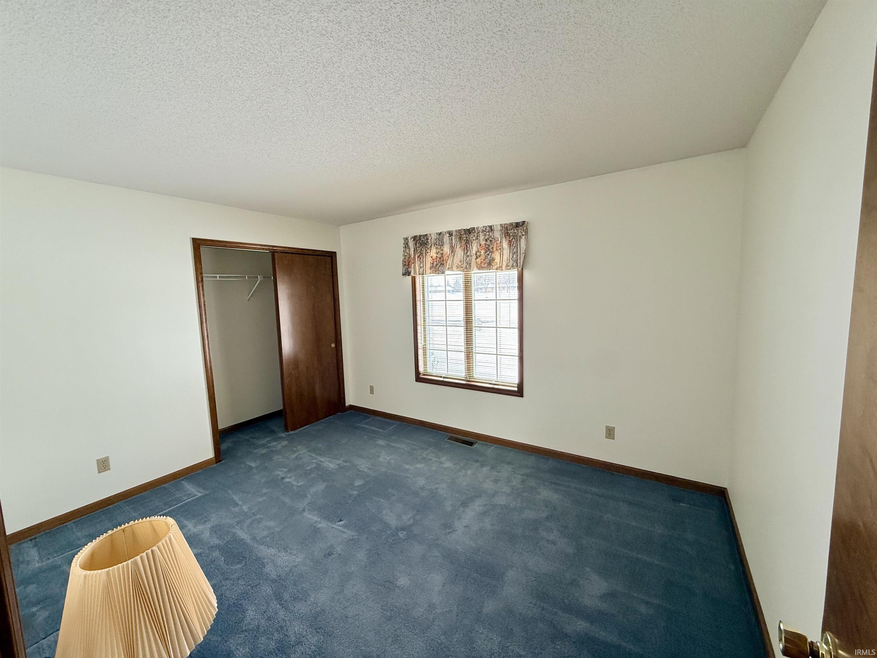 Unfurnished bedroom with carpet floors, a closet, and a textured ceiling