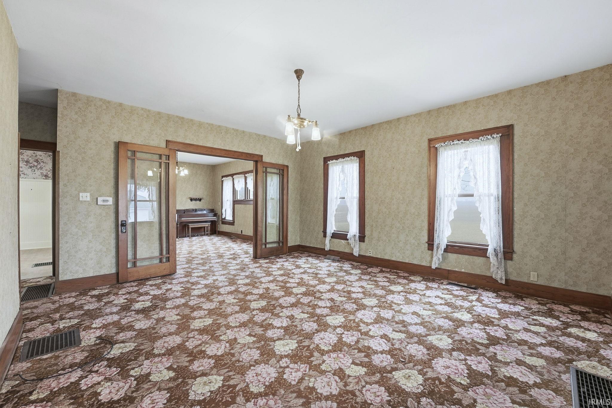 Spare room featuring a chandelier and baseboards