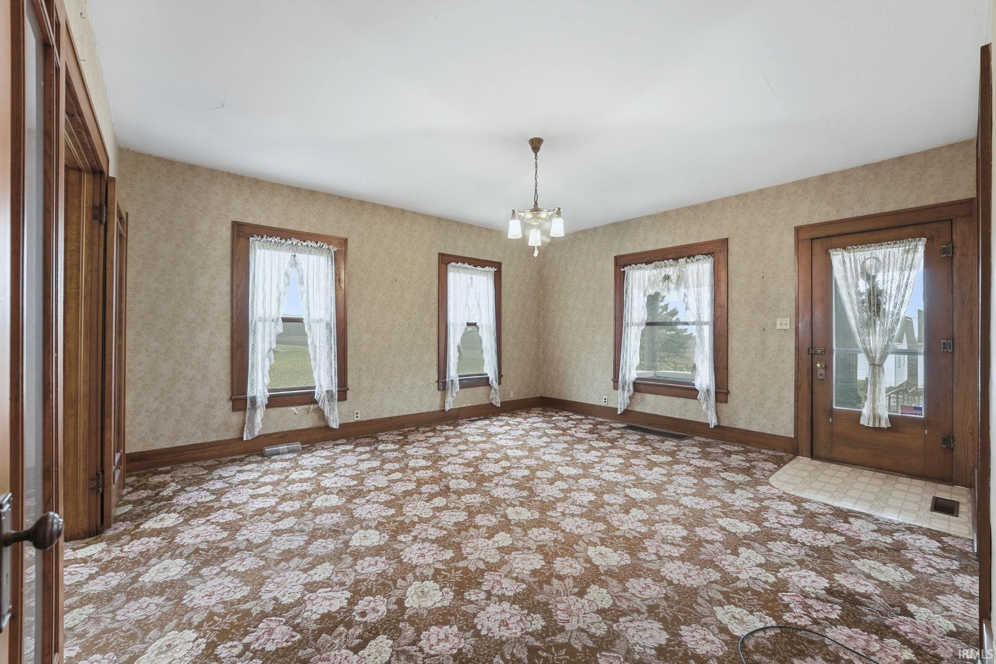 Entryway featuring a chandelier, healthy amount of natural light, wallpapered walls, and carpet floors