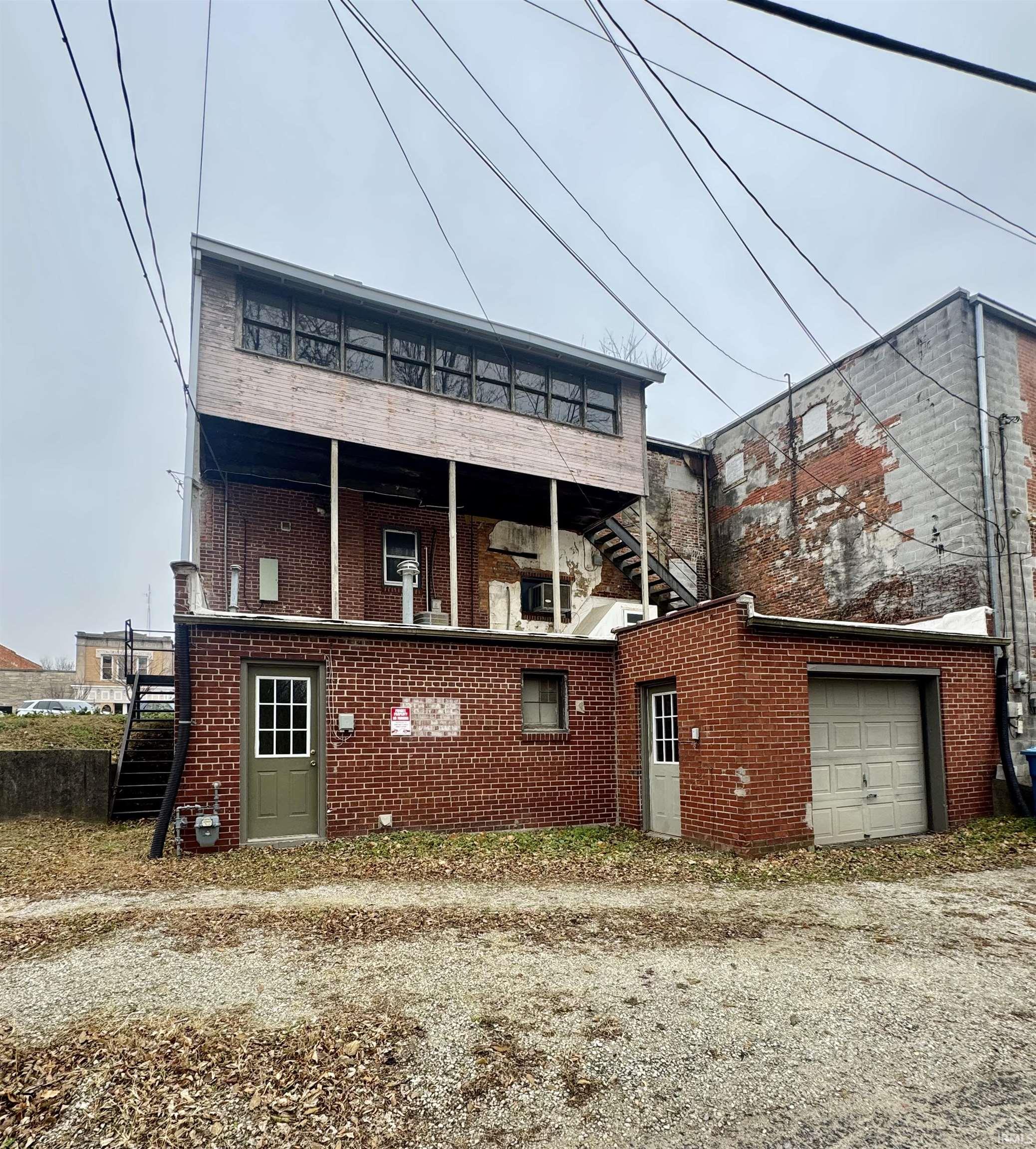 Rear view of property featuring brick siding, a garage, and stairway