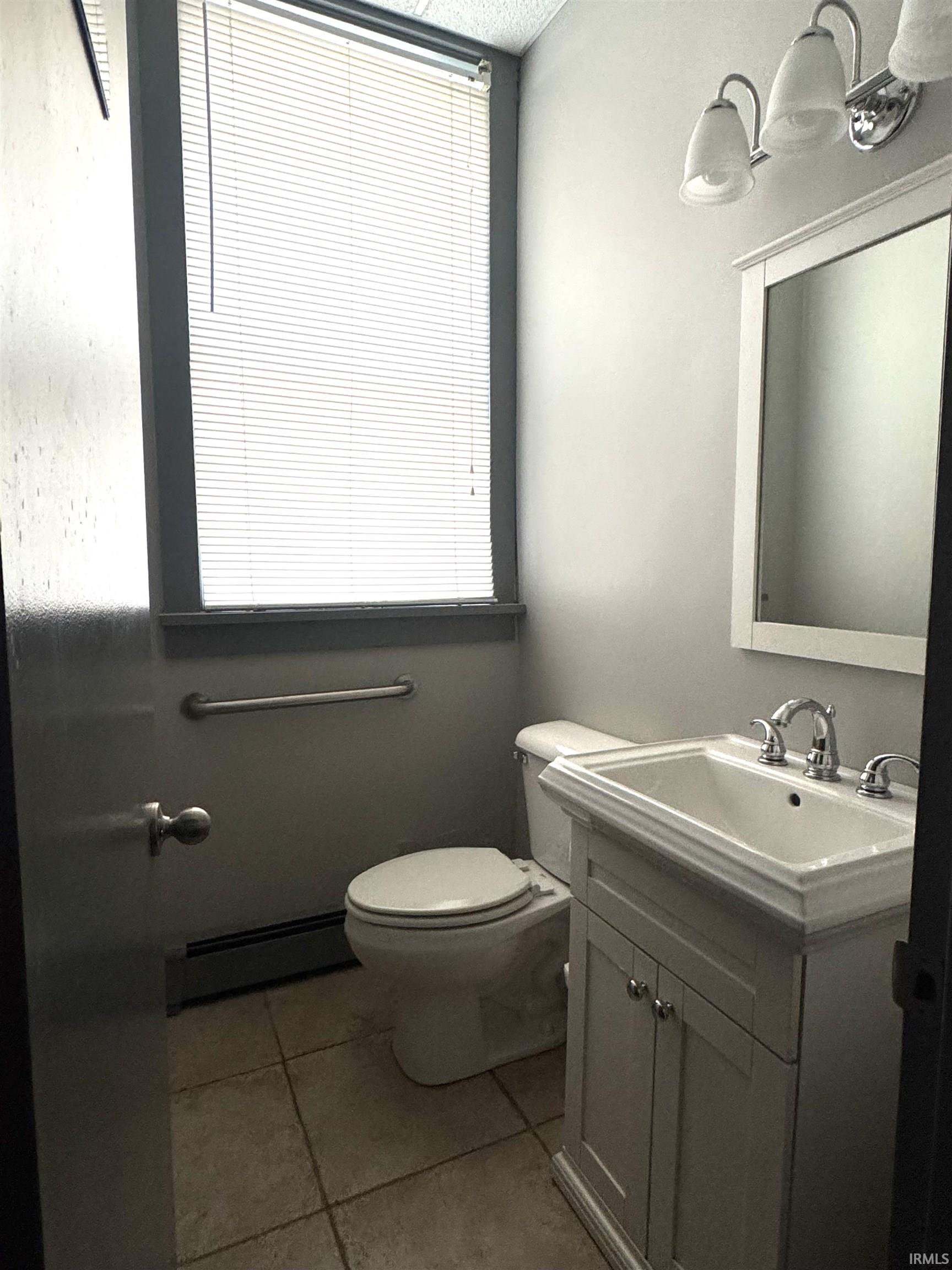 Half bath with vanity, a baseboard radiator, light tile patterned floors, and a textured ceiling