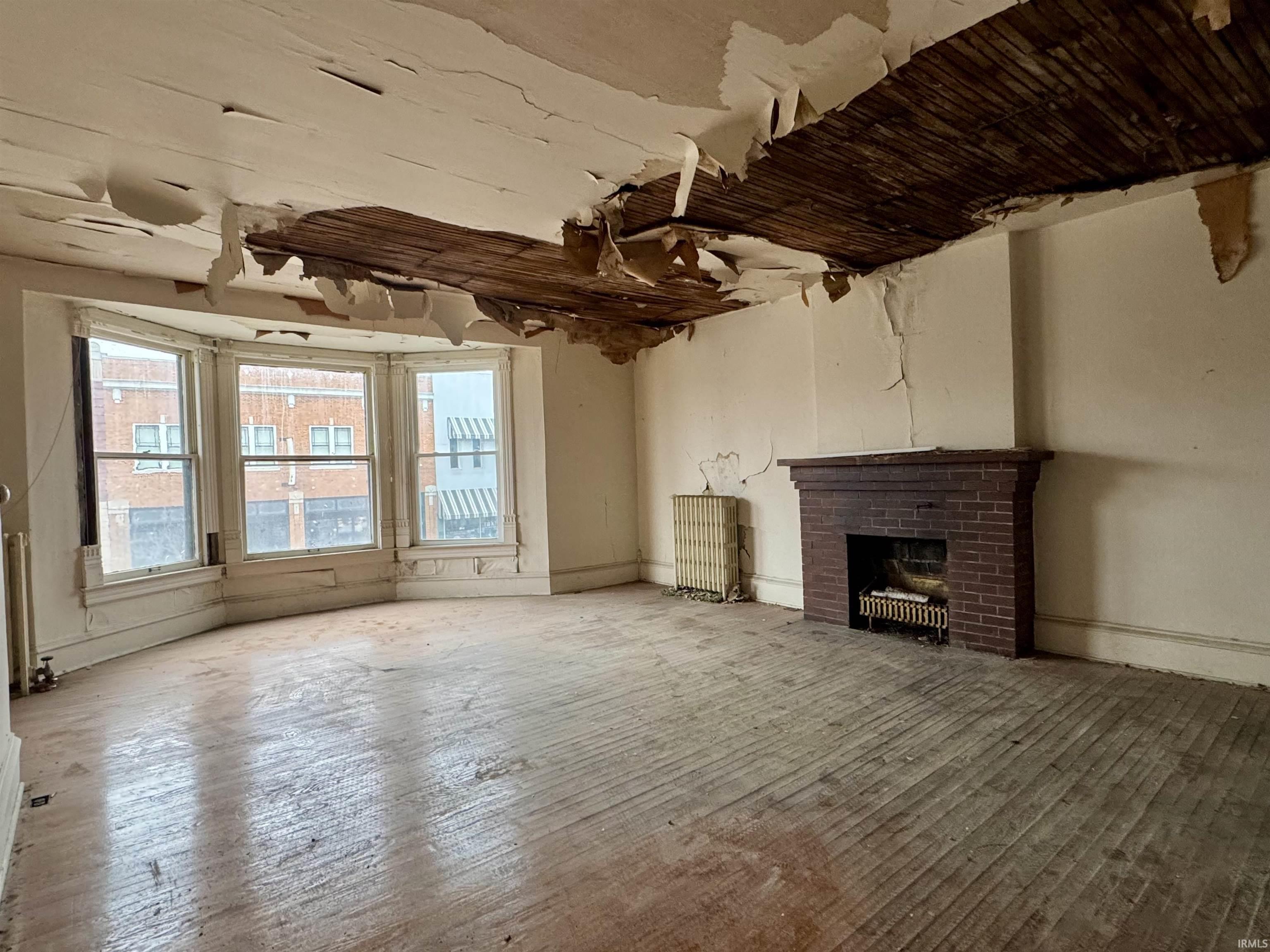 Unfurnished living room with a fireplace, hardwood / wood-style flooring, and radiator heating unit
