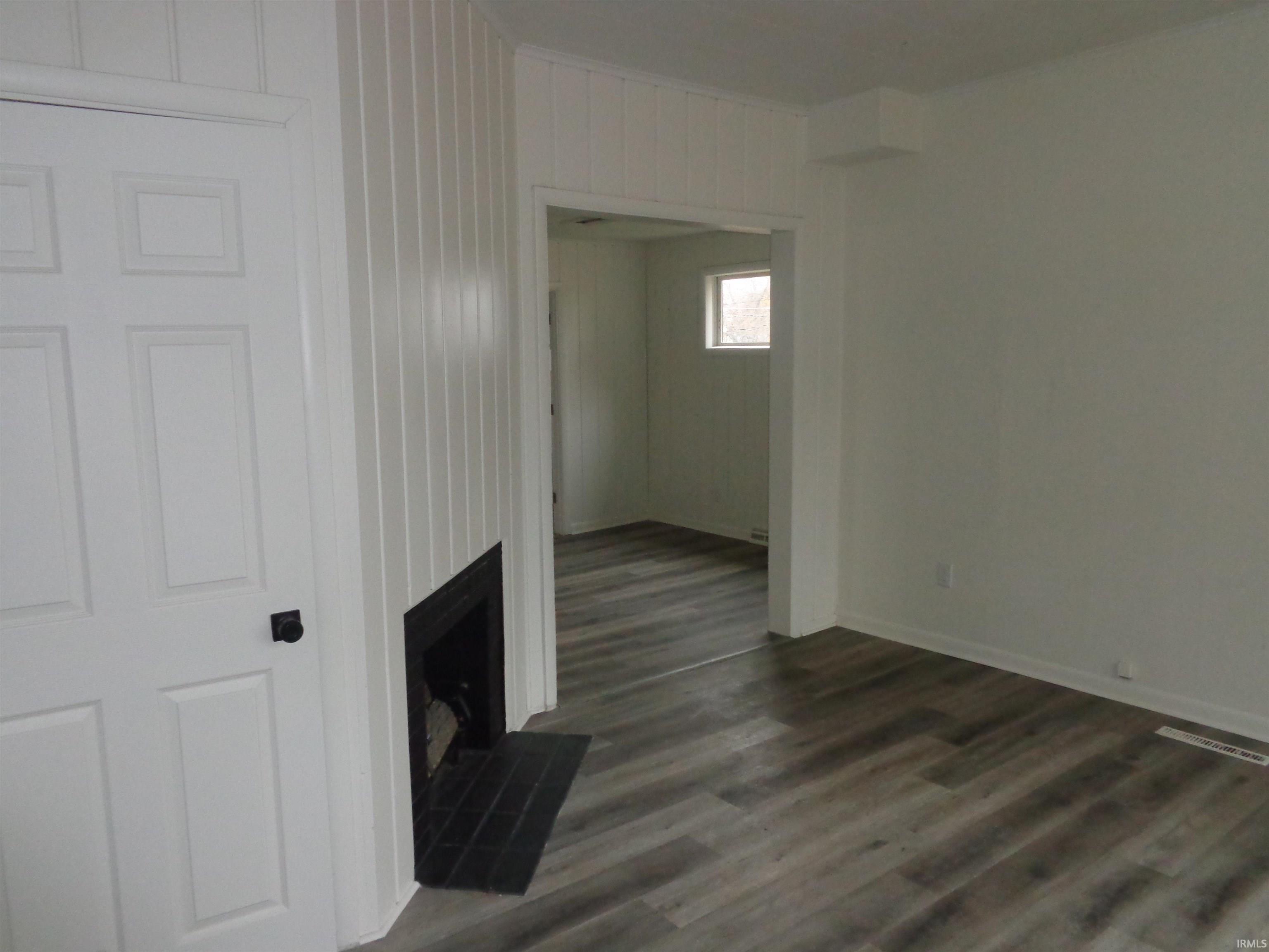 Unfurnished living room featuring dark wood-type flooring and a fireplace
