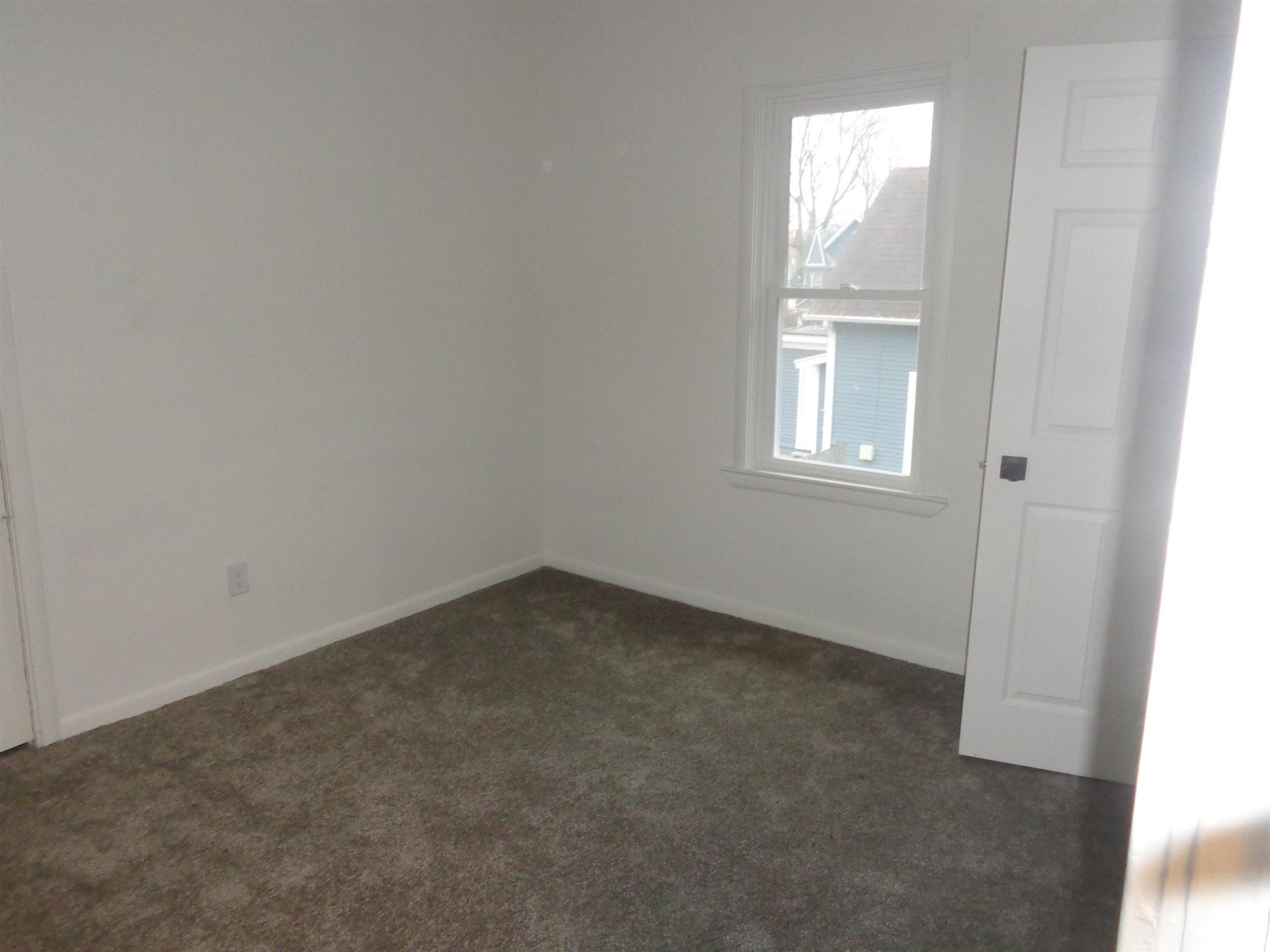 Unfurnished room with dark colored carpet and baseboards
