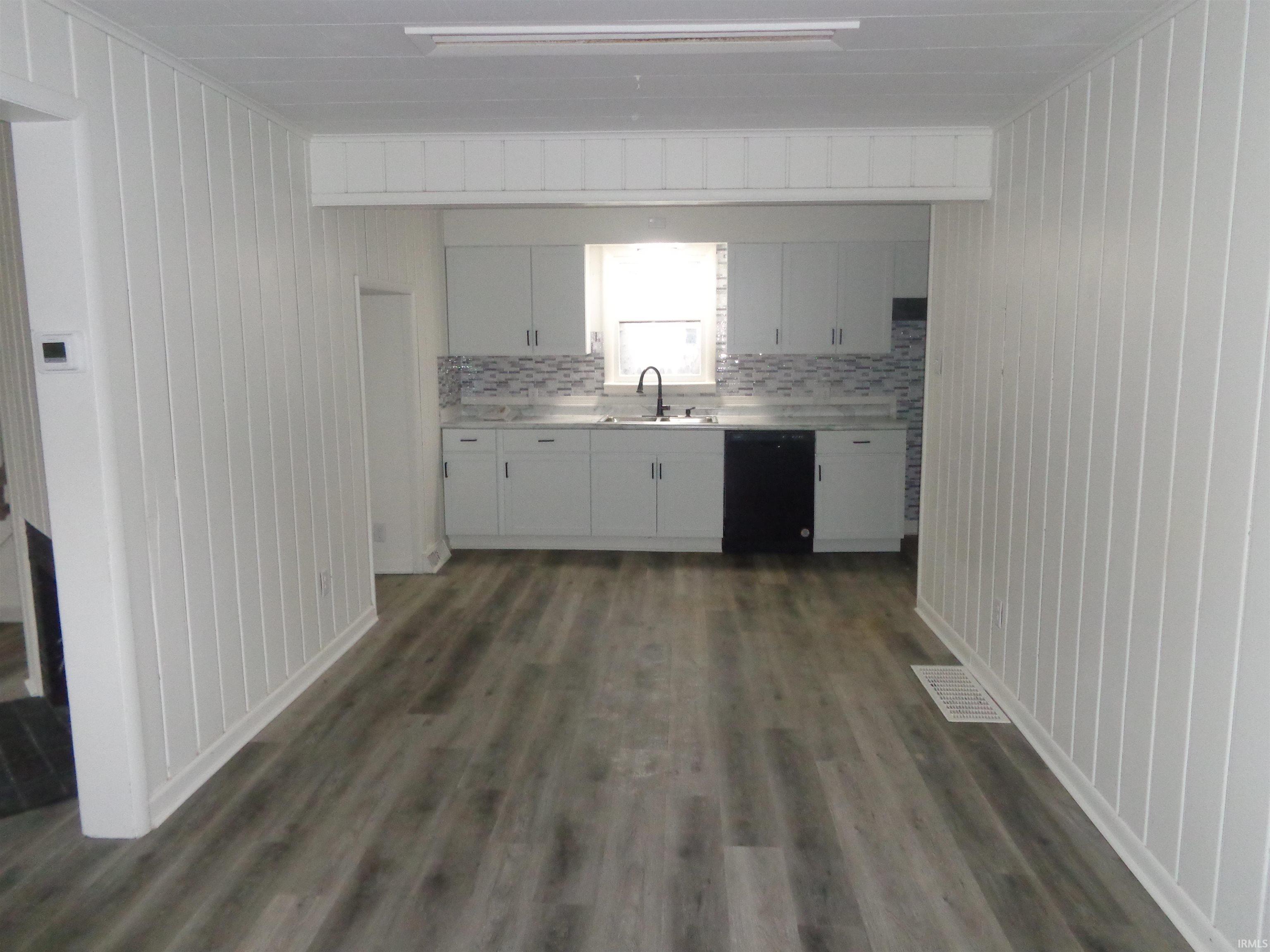 Kitchen with white cabinetry, light countertops, dark wood-type flooring, dishwasher, and tasteful backsplash