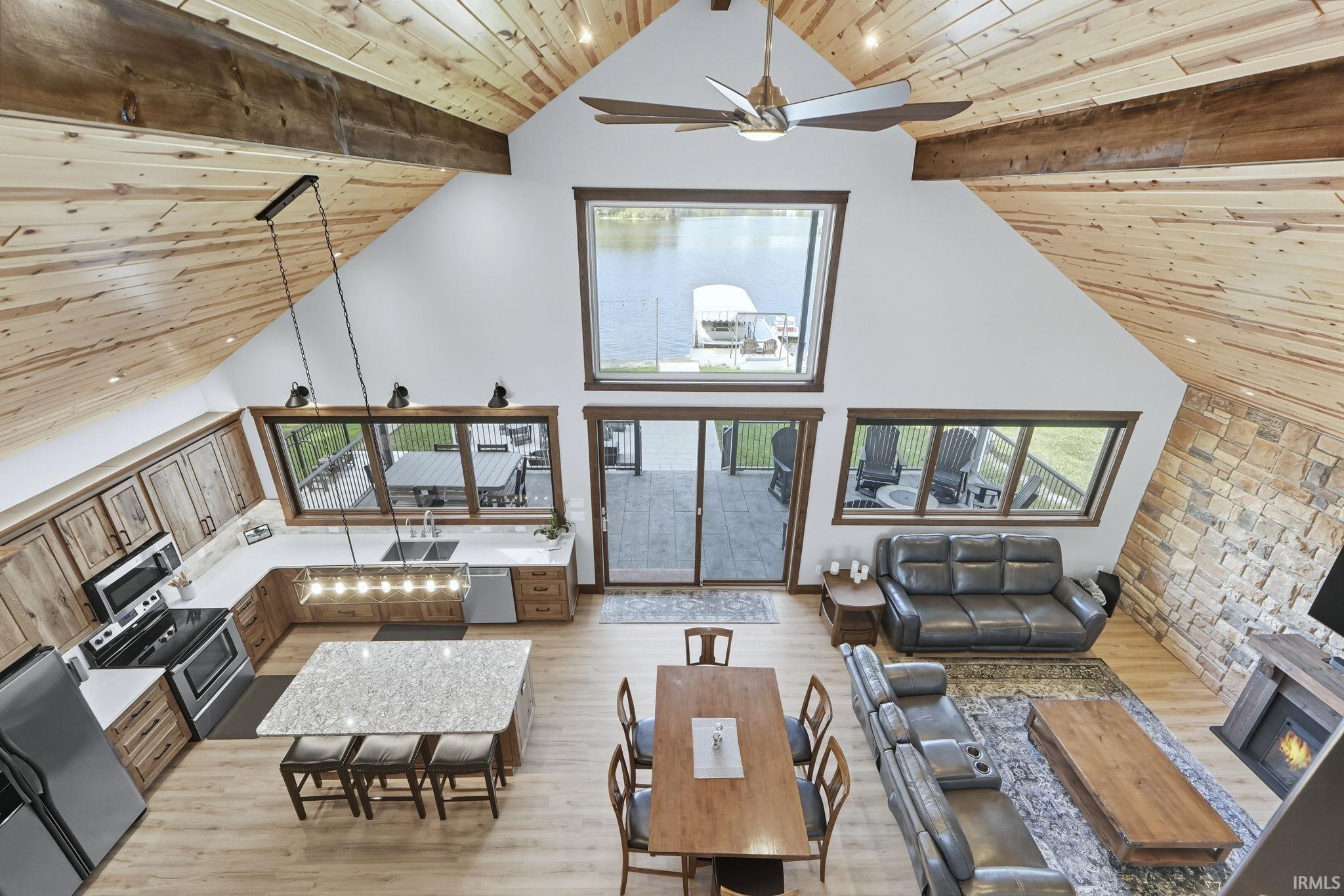 Living room with a wooden ceiling with exposed beams, high vaulted ceiling, light wood-style floors, and a ceiling fan