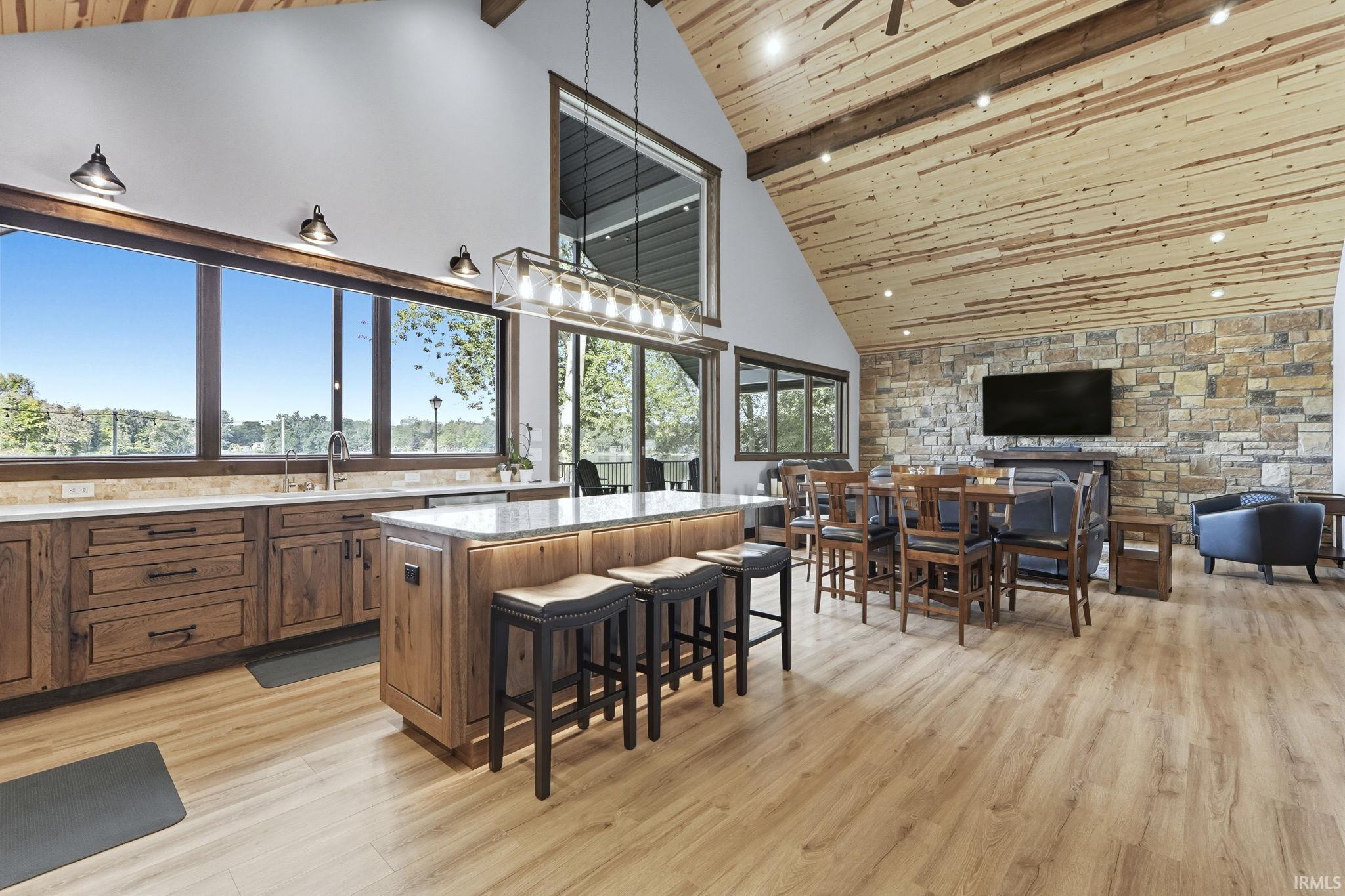 Kitchen featuring a breakfast bar area, high vaulted ceiling, light wood-style floors, a wooden ceiling with exposed beams, and pendant lighting
