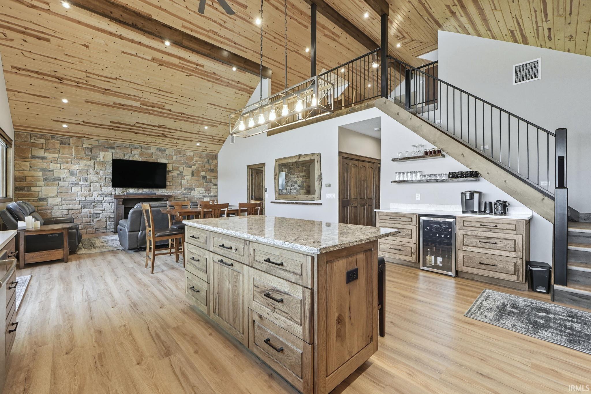 Kitchen featuring a wood ceiling with exposed beams, hanging light fixtures, high vaulted ceiling, wine cooler, and a kitchen island
