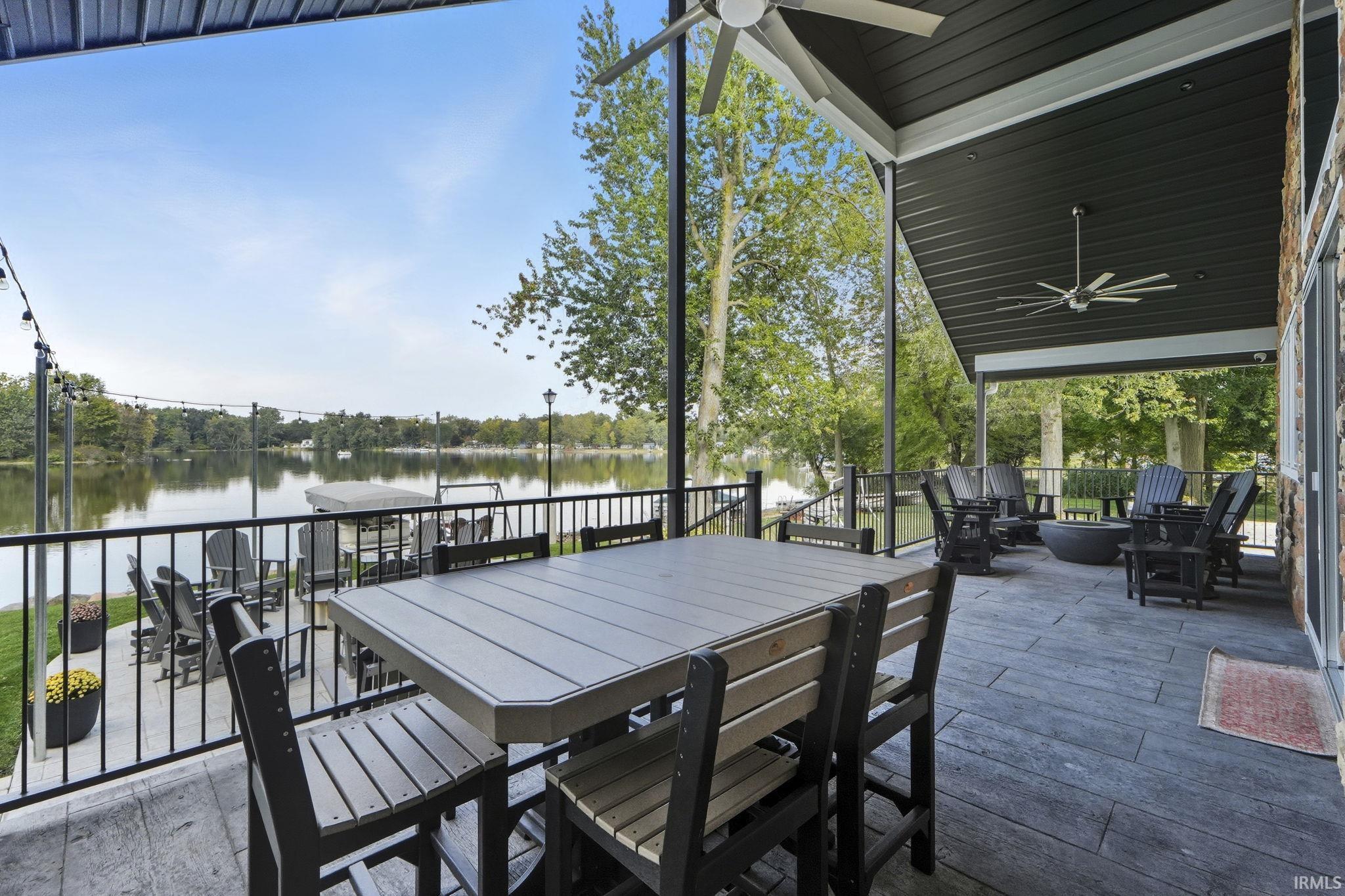 View of patio featuring ceiling fan, outdoor dining space, a deck with water view, and view of wooded area
