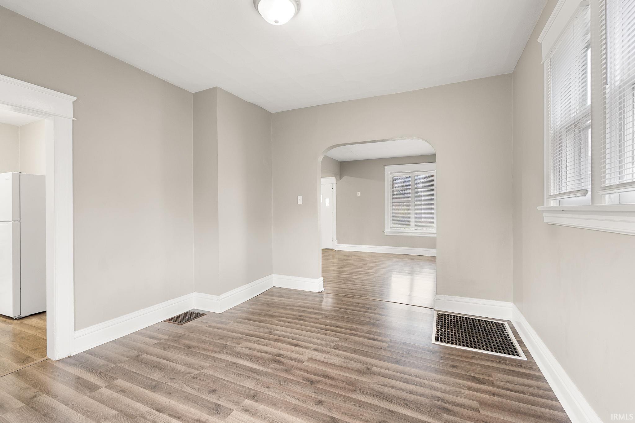 Spare room with arched walkways and light wood finished floors