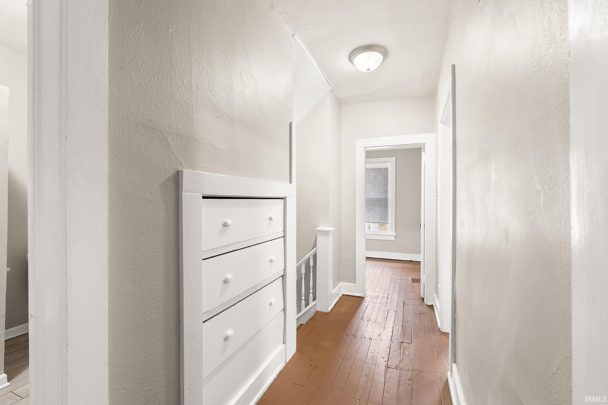 Hall featuring light wood finished floors and a textured wall