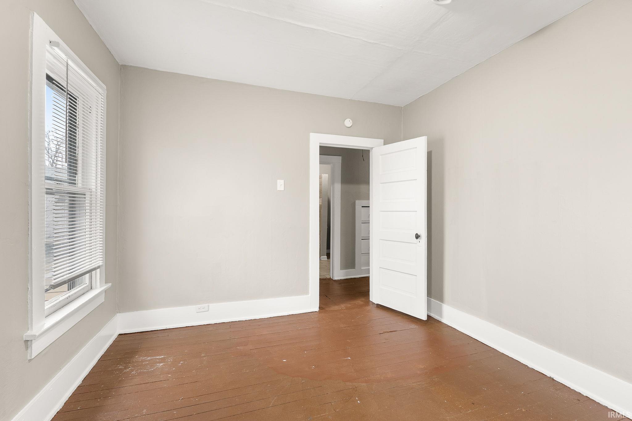 Unfurnished bedroom with dark wood finished floors and baseboards