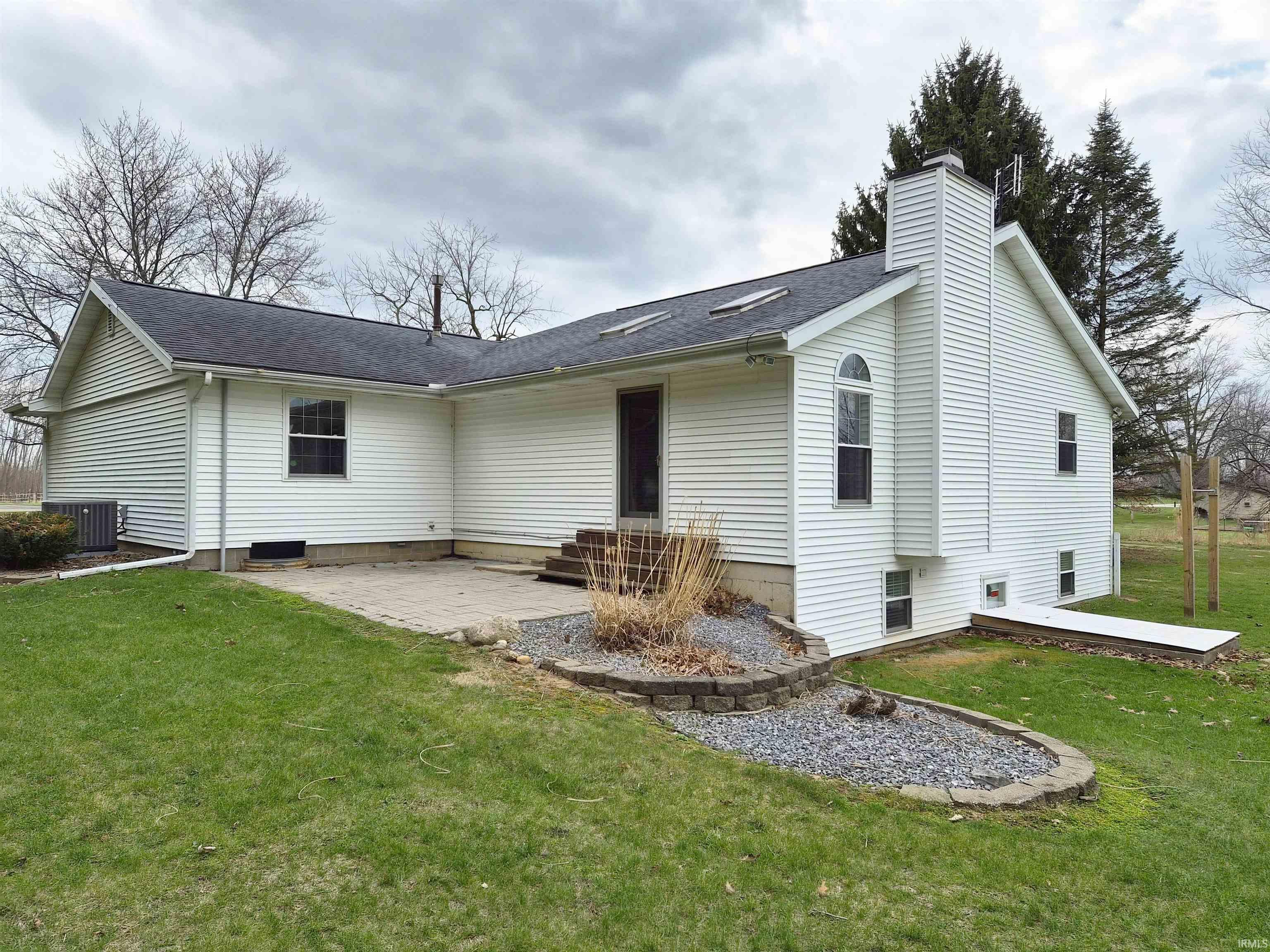 Rear view of property with a patio area, a lawn, a chimney, and a shingled roof
