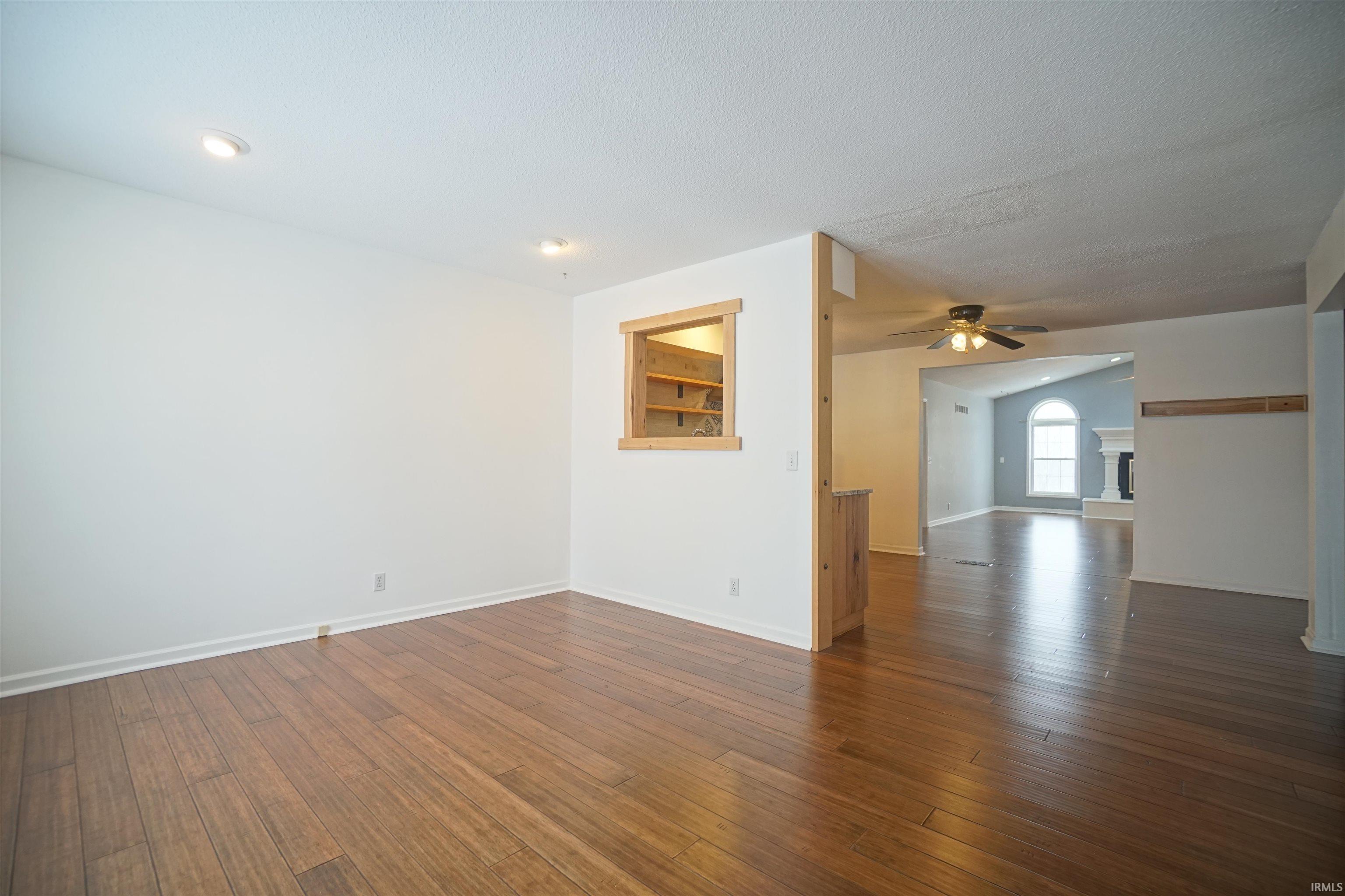 Dining room with dark wood-style floors, arched walkways, ceiling fan, and a textured ceiling