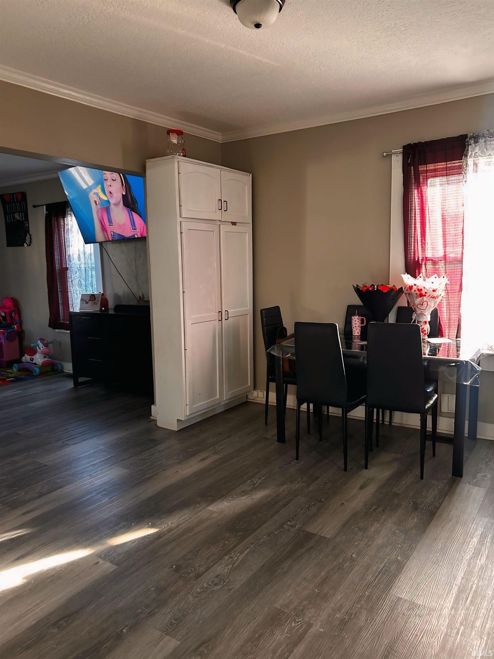 Dining room featuring a textured ceiling, dark wood-type flooring, and ornamental molding