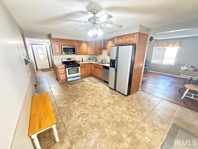 Kitchen with stainless steel appliances, light tile patterned floors, light countertops, and ceiling fan