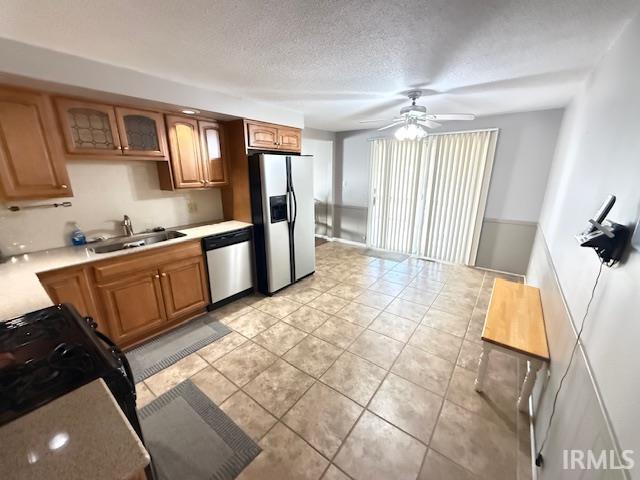 Kitchen featuring light countertops, wood finish cabinets, stainless steel appliances, glass fronted cabinets, and ceiling fan