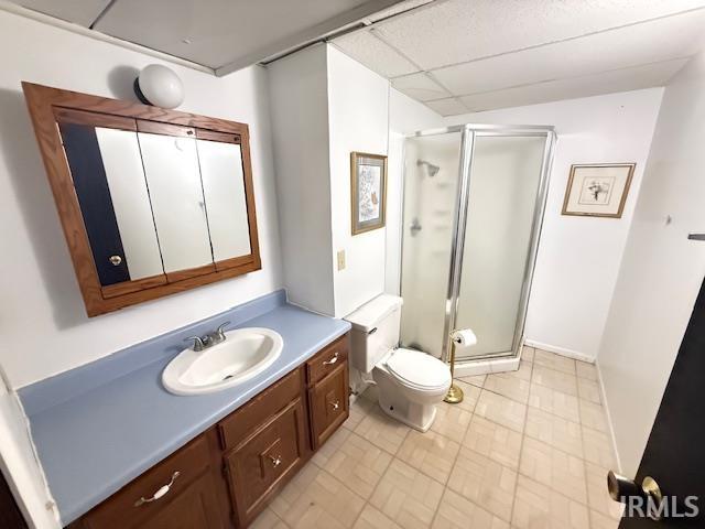 Bathroom featuring a paneled ceiling, a shower stall, and vanity