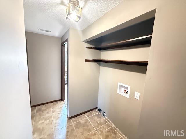 Laundry area with washer hookup, a textured ceiling, and light tile patterned flooring