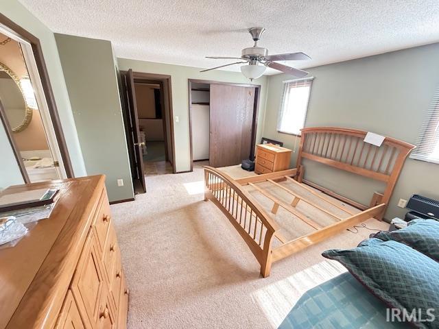 Bedroom with a closet, a textured ceiling, light colored carpet, and ceiling fan