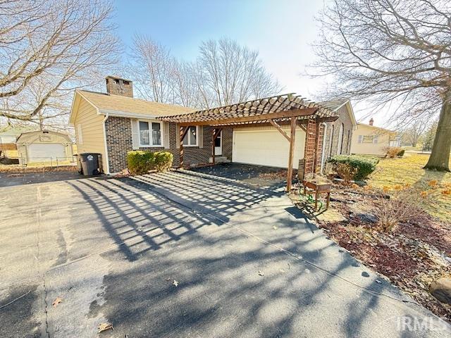 Ranch-style house with concrete driveway, a garage, a pergola, a chimney, and a patio