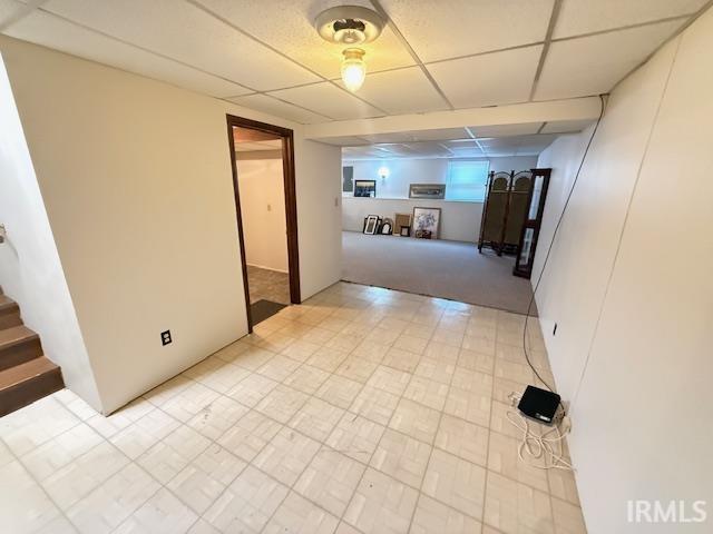 Unfurnished room featuring a drop ceiling and stairway