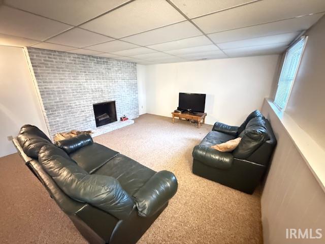 Carpeted living area featuring a paneled ceiling and a large fireplace