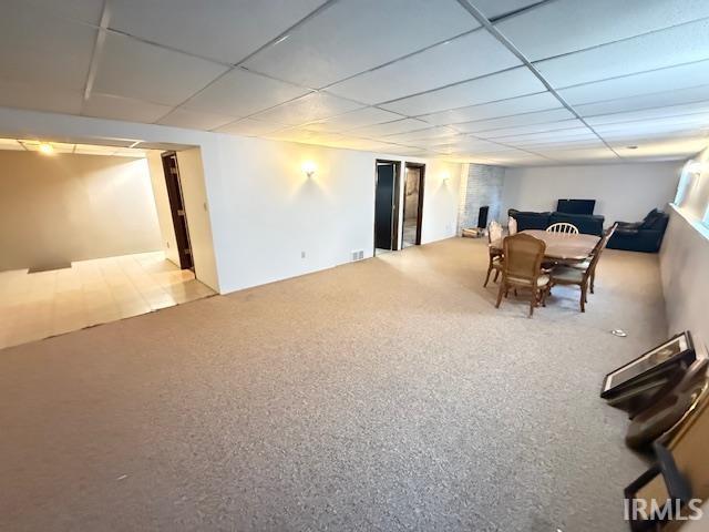 Carpeted dining space featuring a paneled ceiling