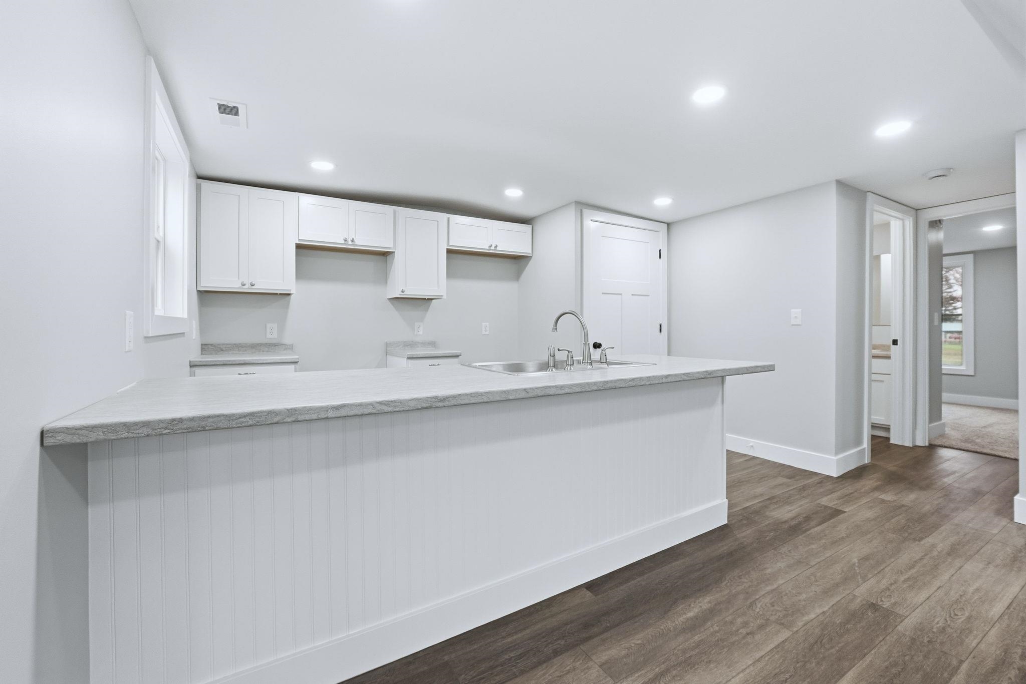 Kitchen featuring white cabinets, dark wood-style floors, light stone countertops, recessed lighting, and a peninsula