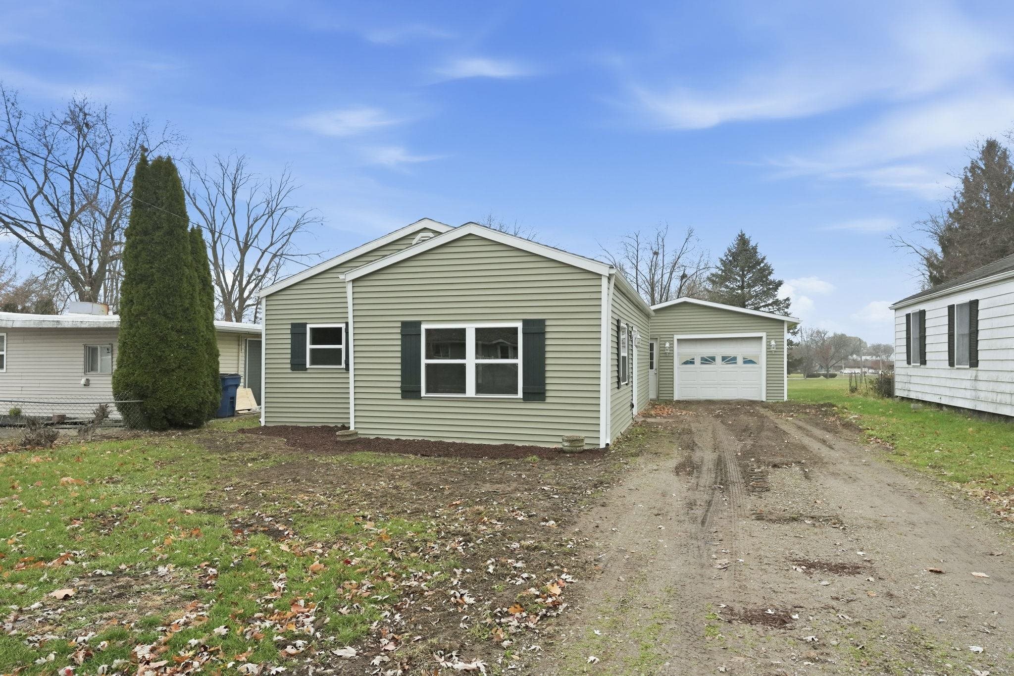 View of home's exterior featuring dirt driveway, a garage, and a lawn