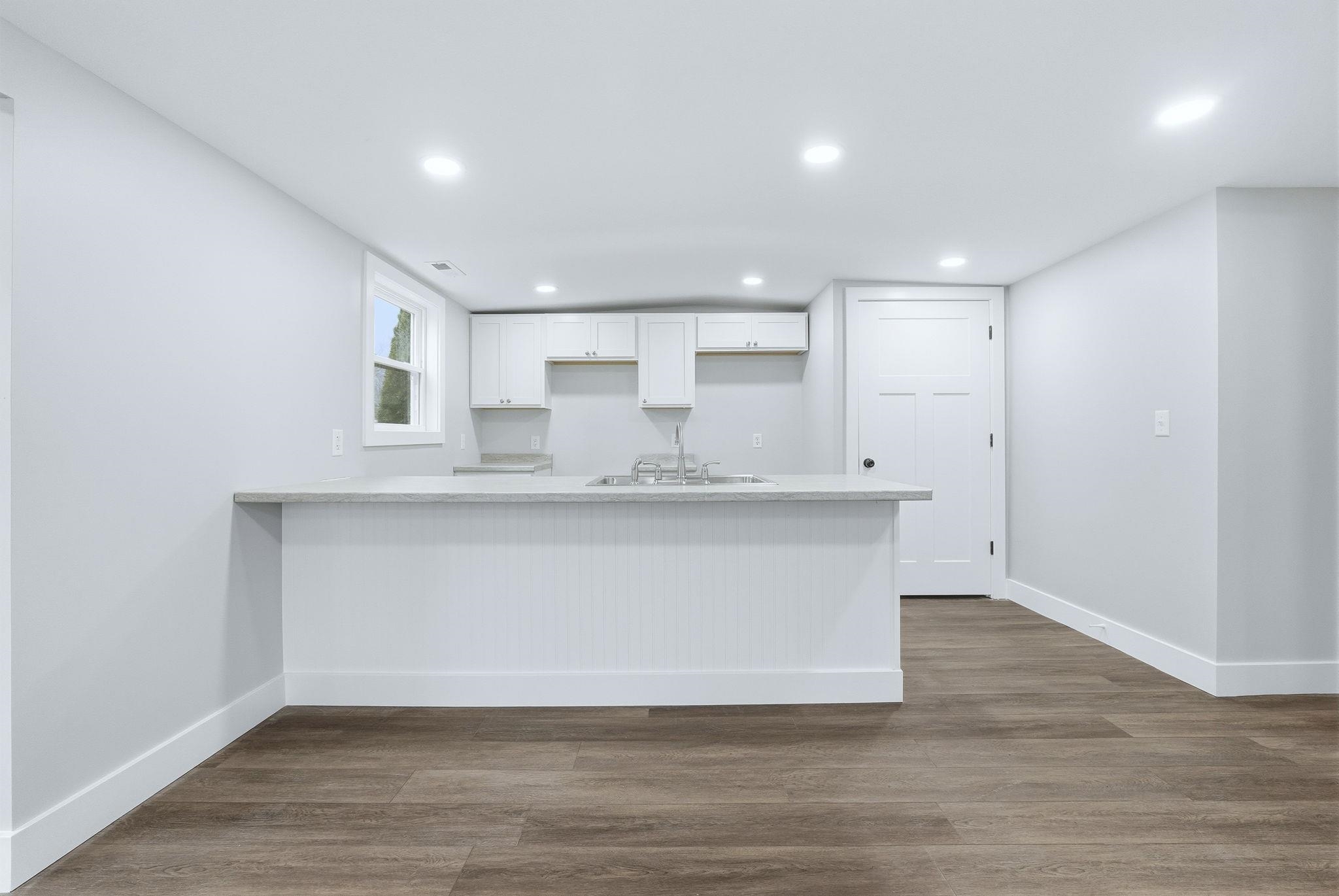Kitchen featuring a peninsula, white cabinets, dark wood-style flooring, and recessed lighting
