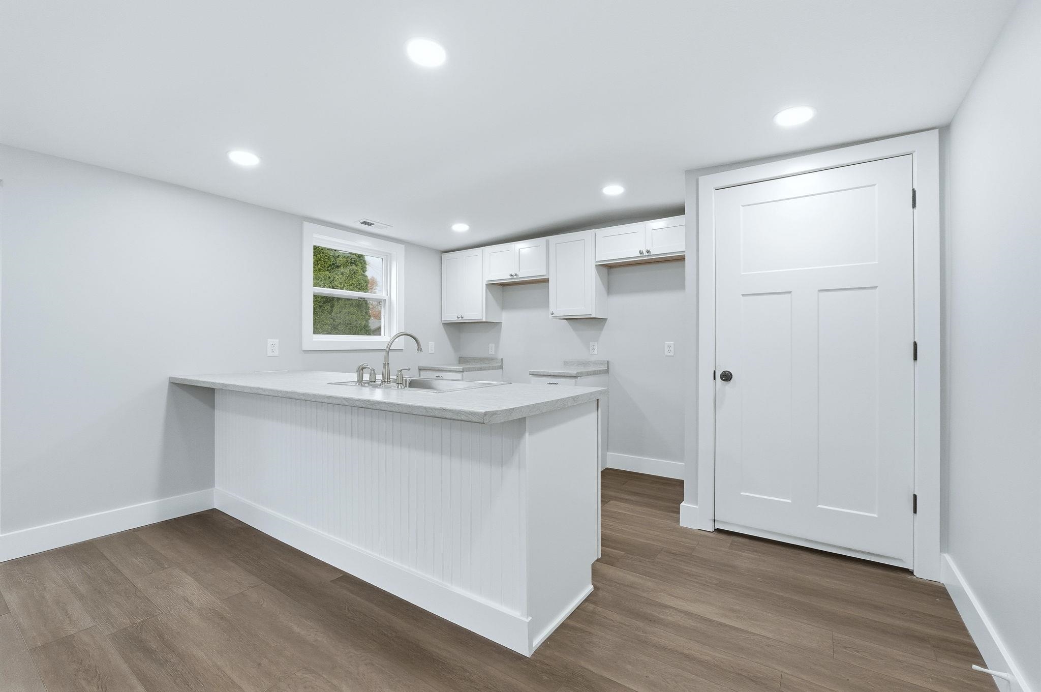 Kitchen featuring white cabinetry, a peninsula, dark wood-style floors, recessed lighting, and light stone countertops