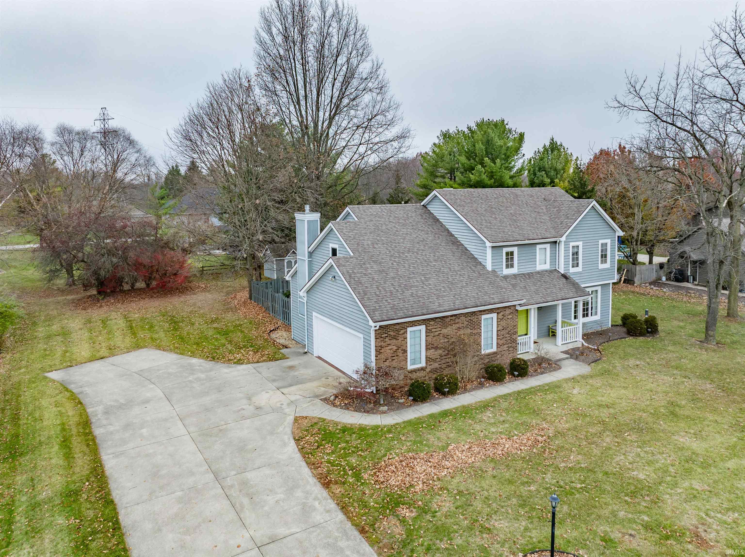 Traditional-style house featuring a front yard, roof with shingles, brick siding, and driveway