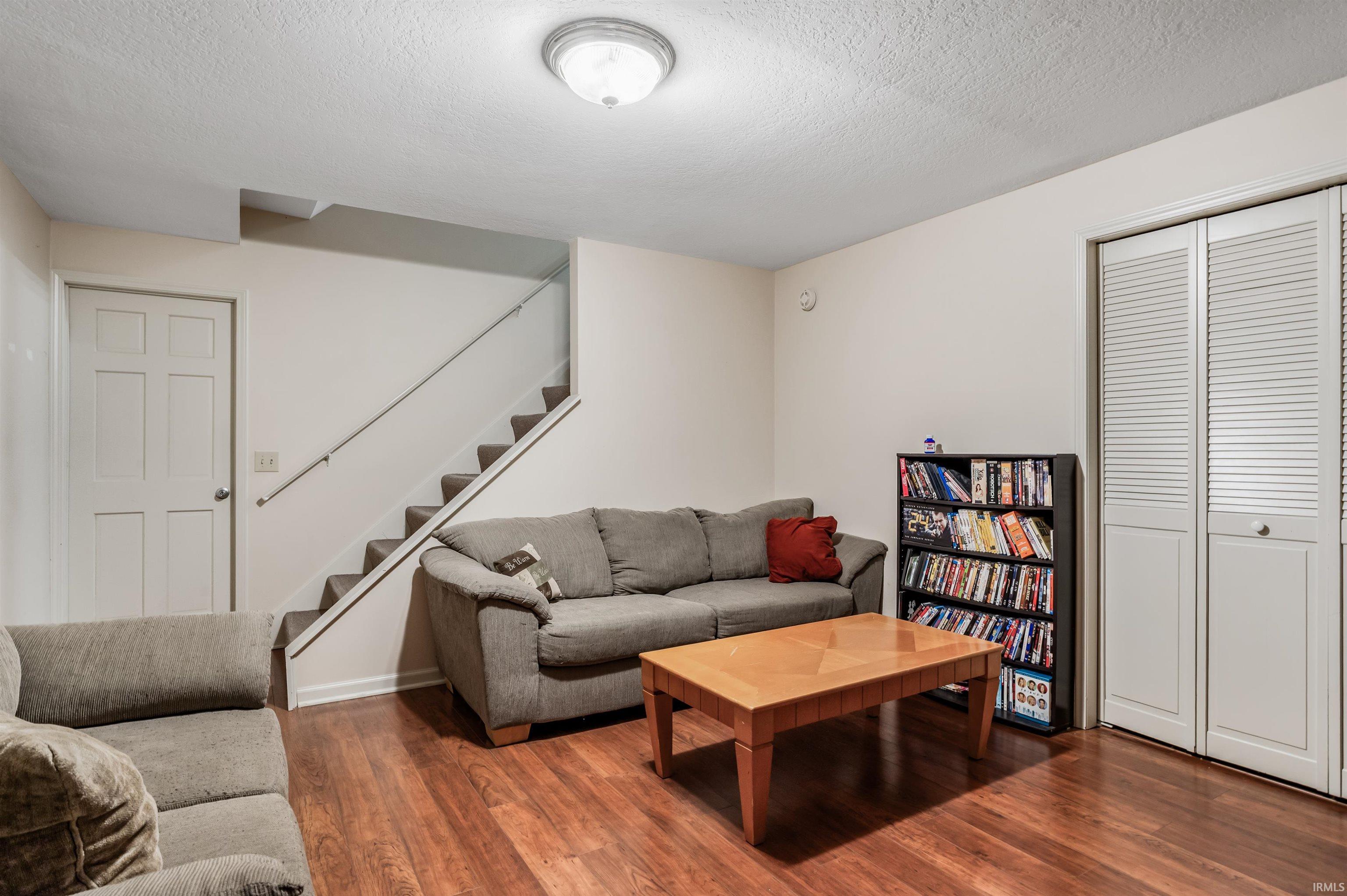 Living room with a textured ceiling, wood finished floors, and stairs