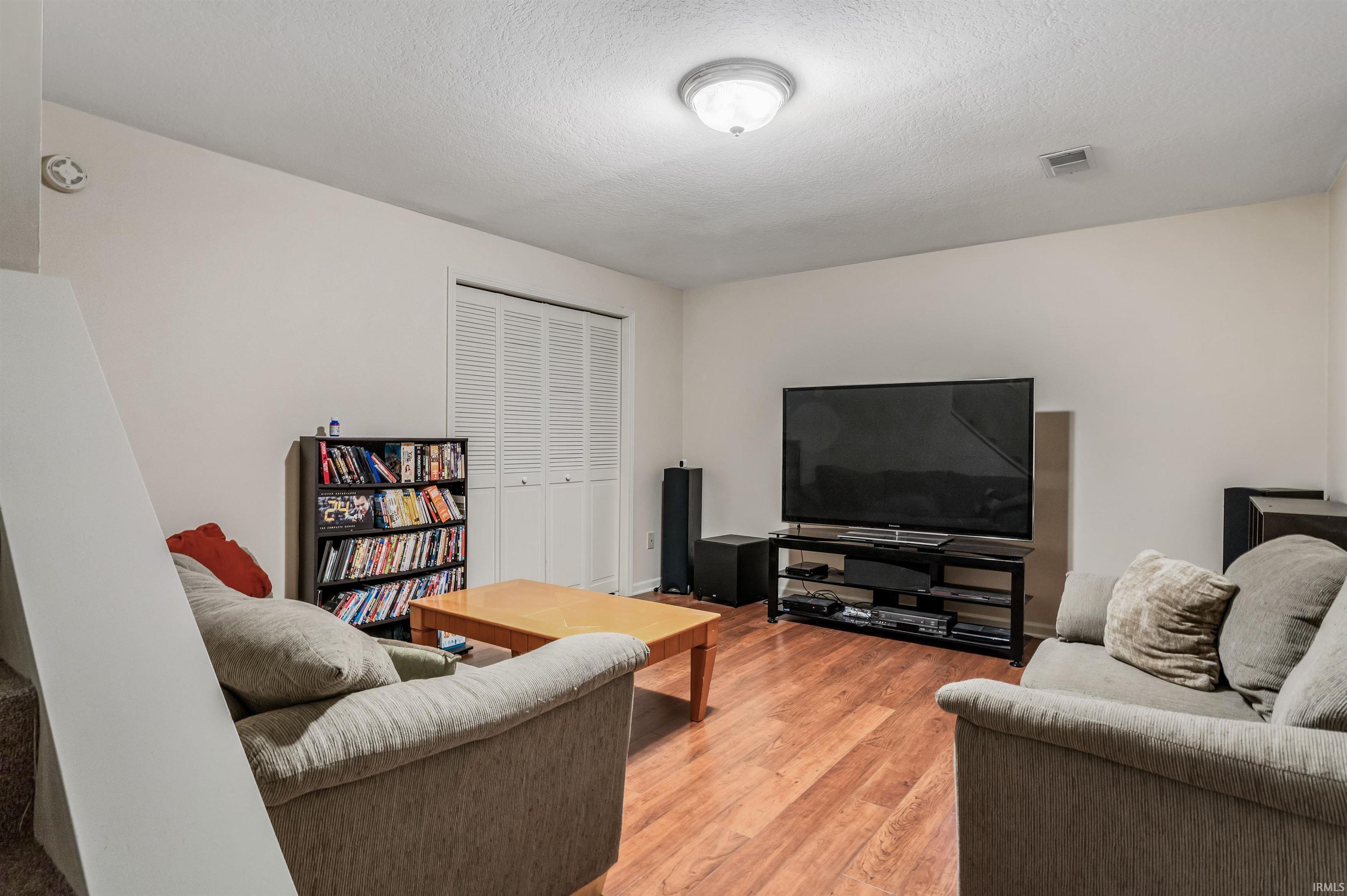 Living area featuring light wood finished floors and a textured ceiling