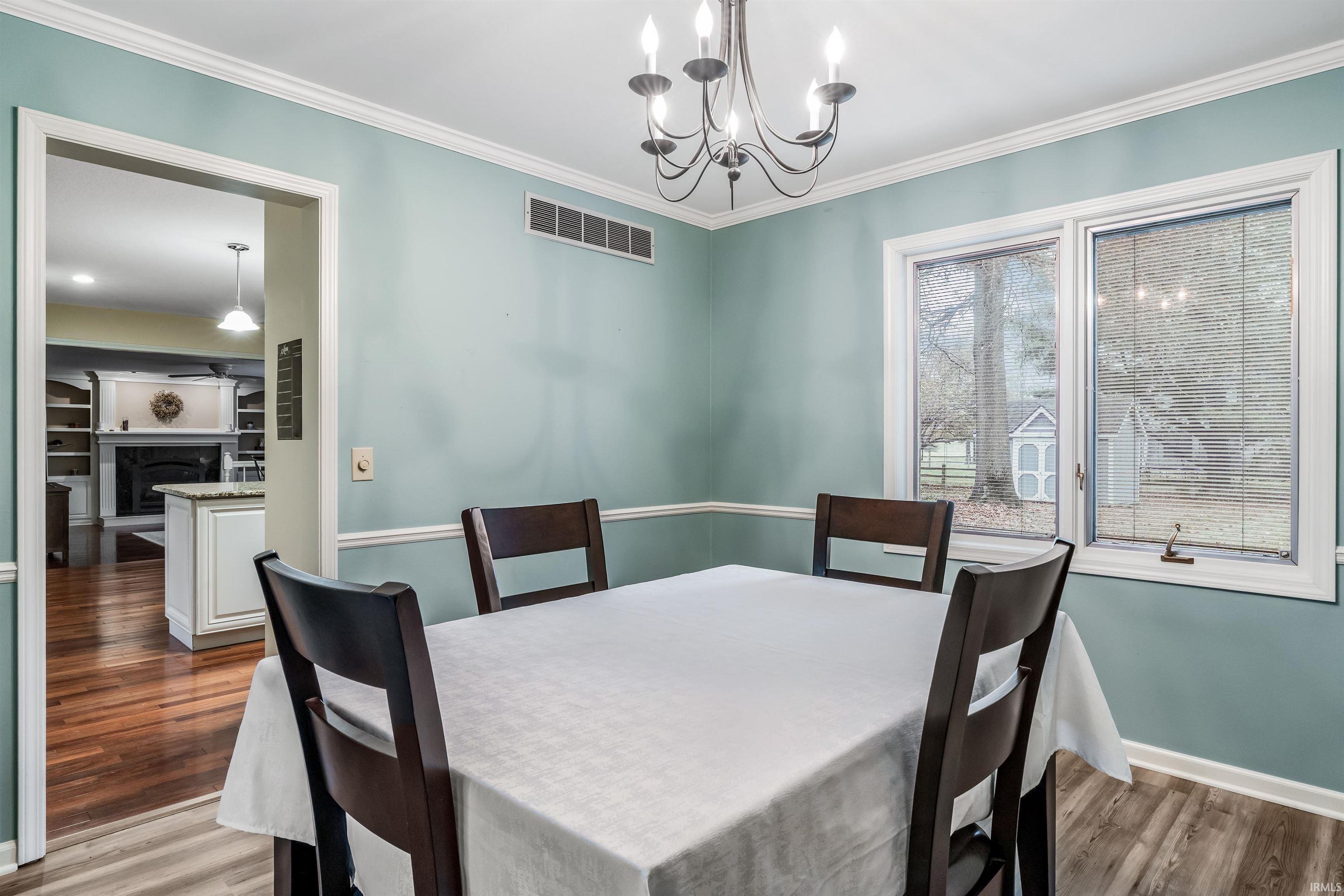 Dining room with ornamental molding, a chandelier, dark wood-style flooring, and a fireplace